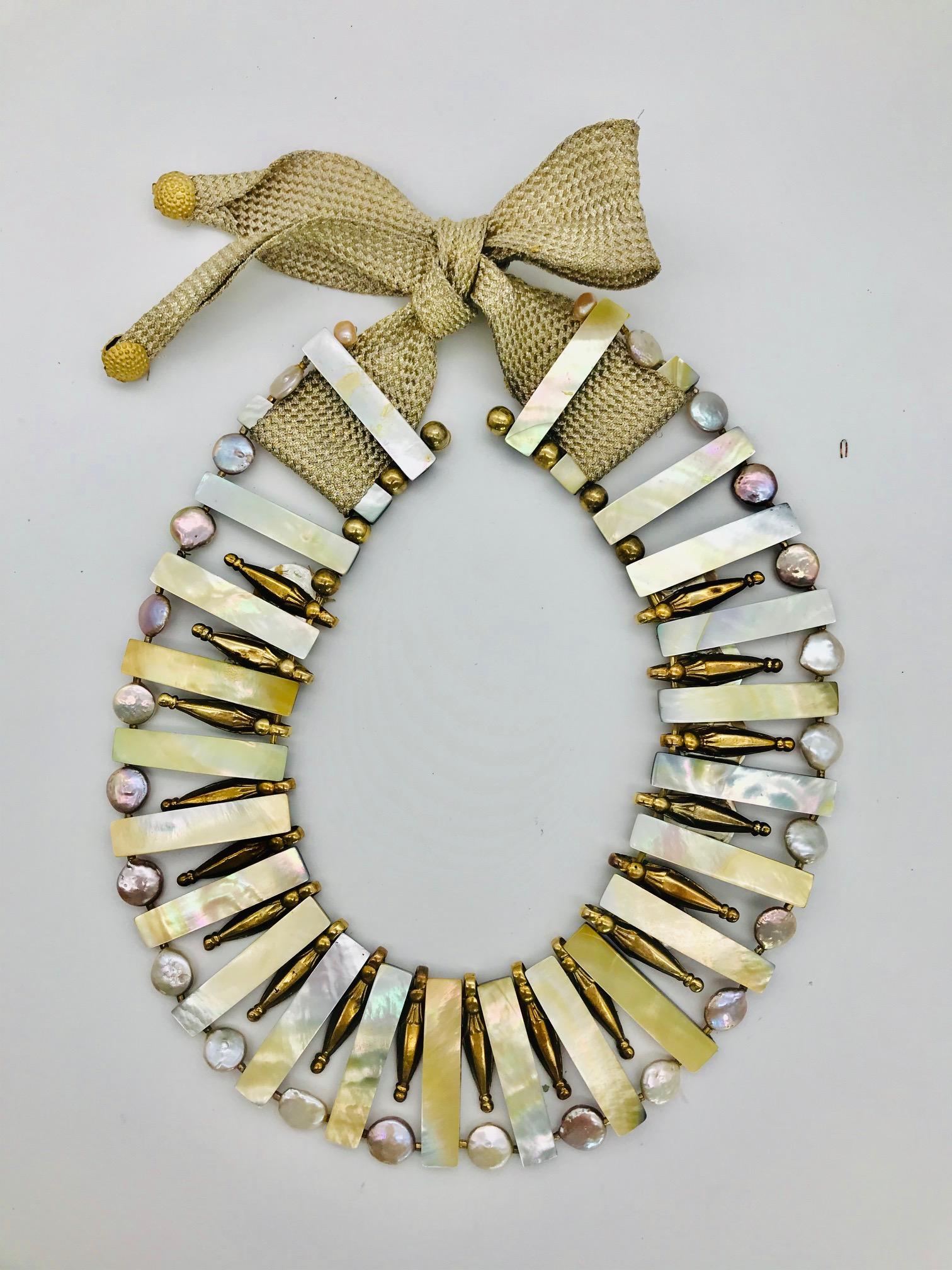 
This White Mother of Pearl  Statement Necklace is up-cycled from  antique and contemporary elements. The necklace is made from White mother of pearl beads , gold plated Antique silver beads , Coin pearls and French Deco ribbon with golden