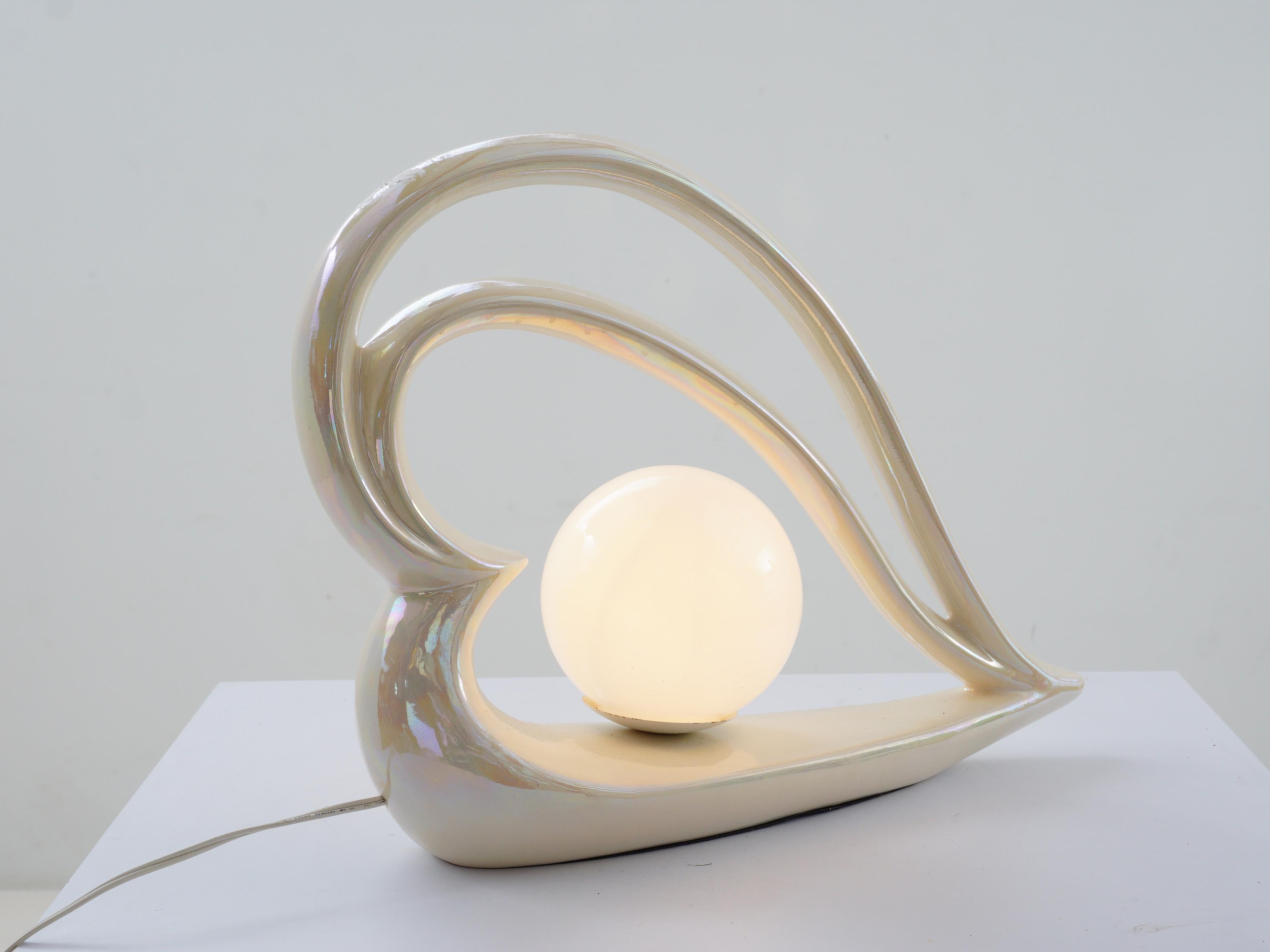 La lampe qui donnera à votre espace une dose de glam postmoderne ! Avec son éclat irisé, cette lampe de table à cœur en céramique n'est pas une simple source de lumière, c'est une œuvre d'art tout droit sortie d'un rêve des années 80.

- 14.25 