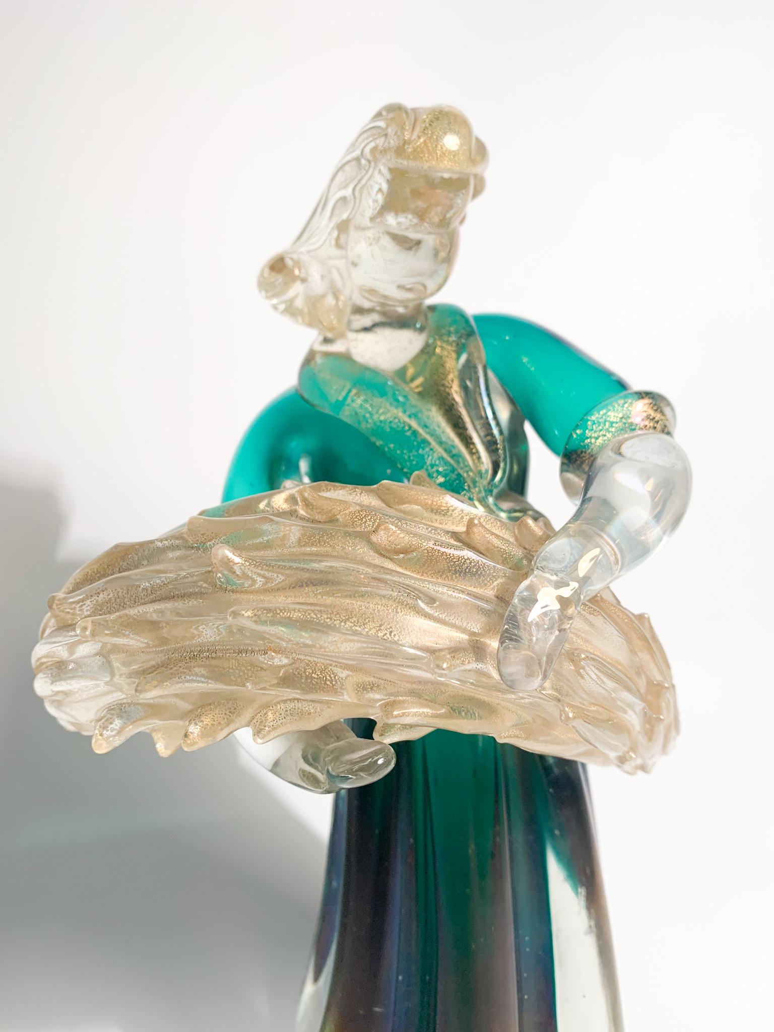 Scultura in vetro di Murano verde cangiante e foglie d'oro, raffigurante una signora con spighe di grano, realizzata da Archimede Seguo negli anni '40.

Ø cm 12 h cm 23