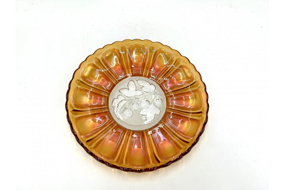 A platter made of iridescent glass, carnival glass, produced in Huta Szkla Gospodarczy Hortensja. Catalog No. 36a. Iridescent orange collar, the bottom decorated with a pressed raspberry branch.

Very good condition.

Measures: Height 3 cm,