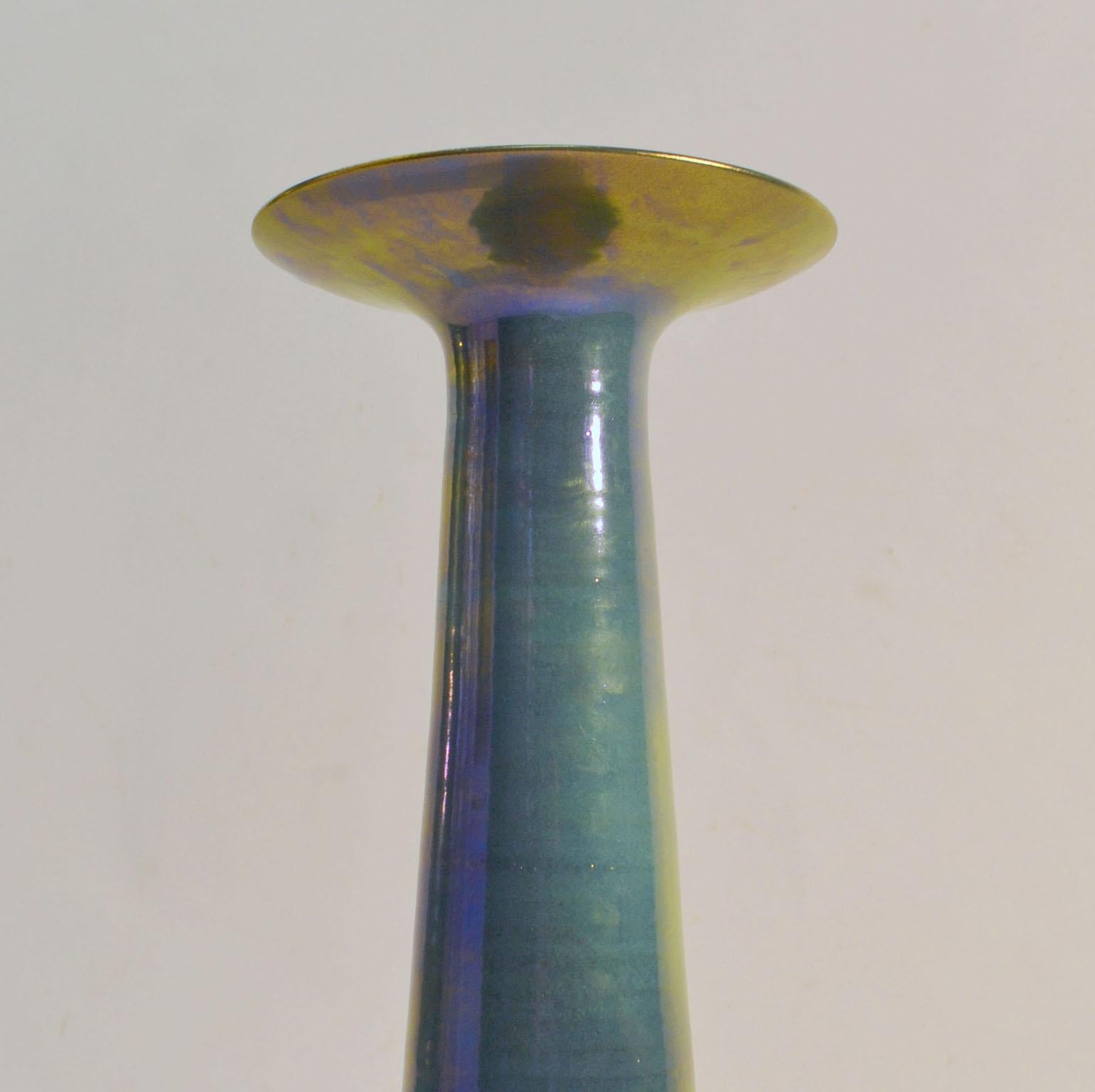 Elongated cone shaped hand-turned vase with exaggerated lip has an iridescent glaze in the dominant colour of turquoise flowing to sky-blue, purple and contrasting mustard-yellow. This vase is an exercise of craftsmanship by the potter in the