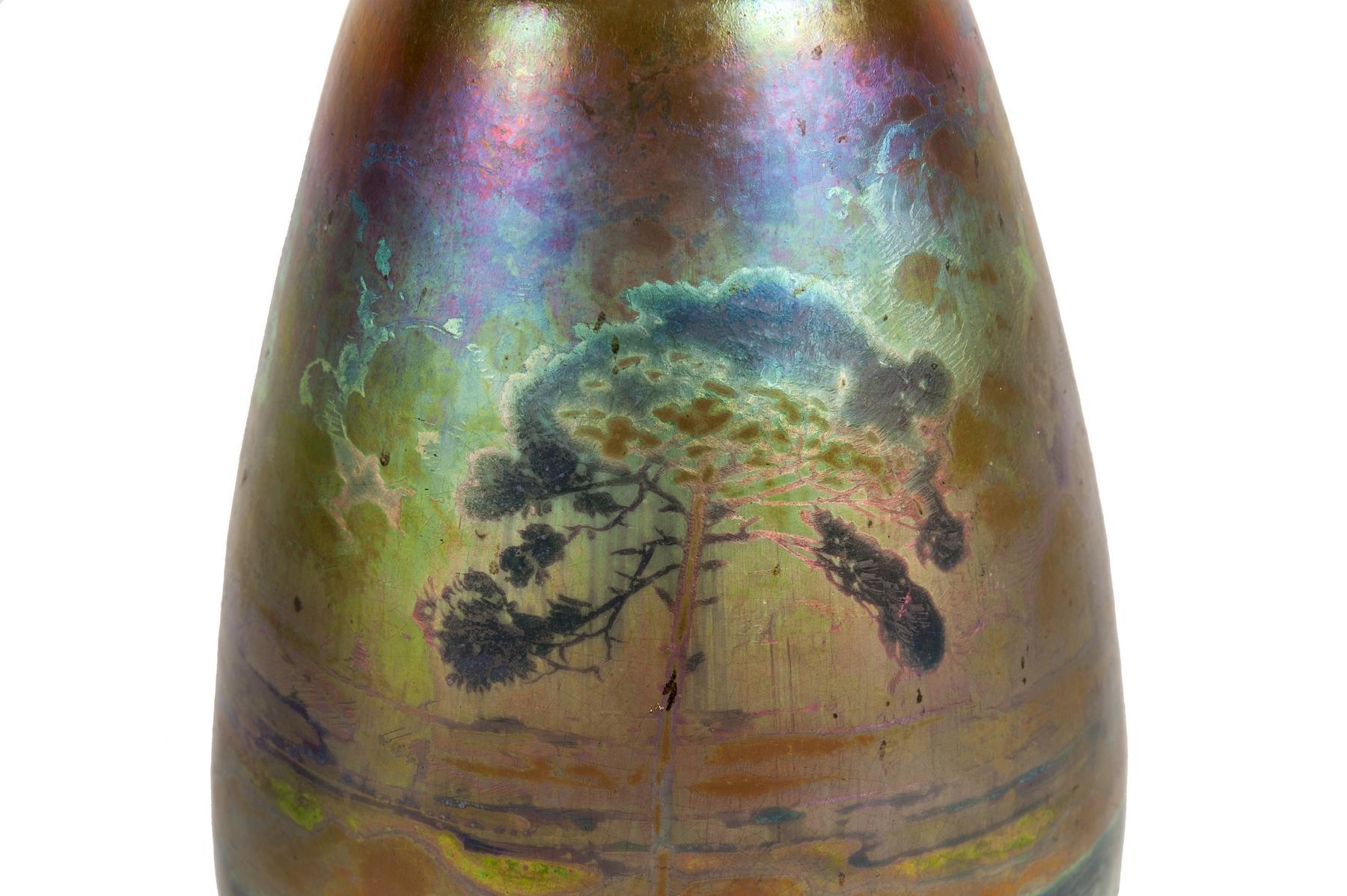 This iridescent vase presents a charming and picturesque Mediterranean landscape. In particular, we can recognize an umbrella pine tree behind which unfolds what appears to be a cliff-lined cove.

The Massier family had been living in Vallauris