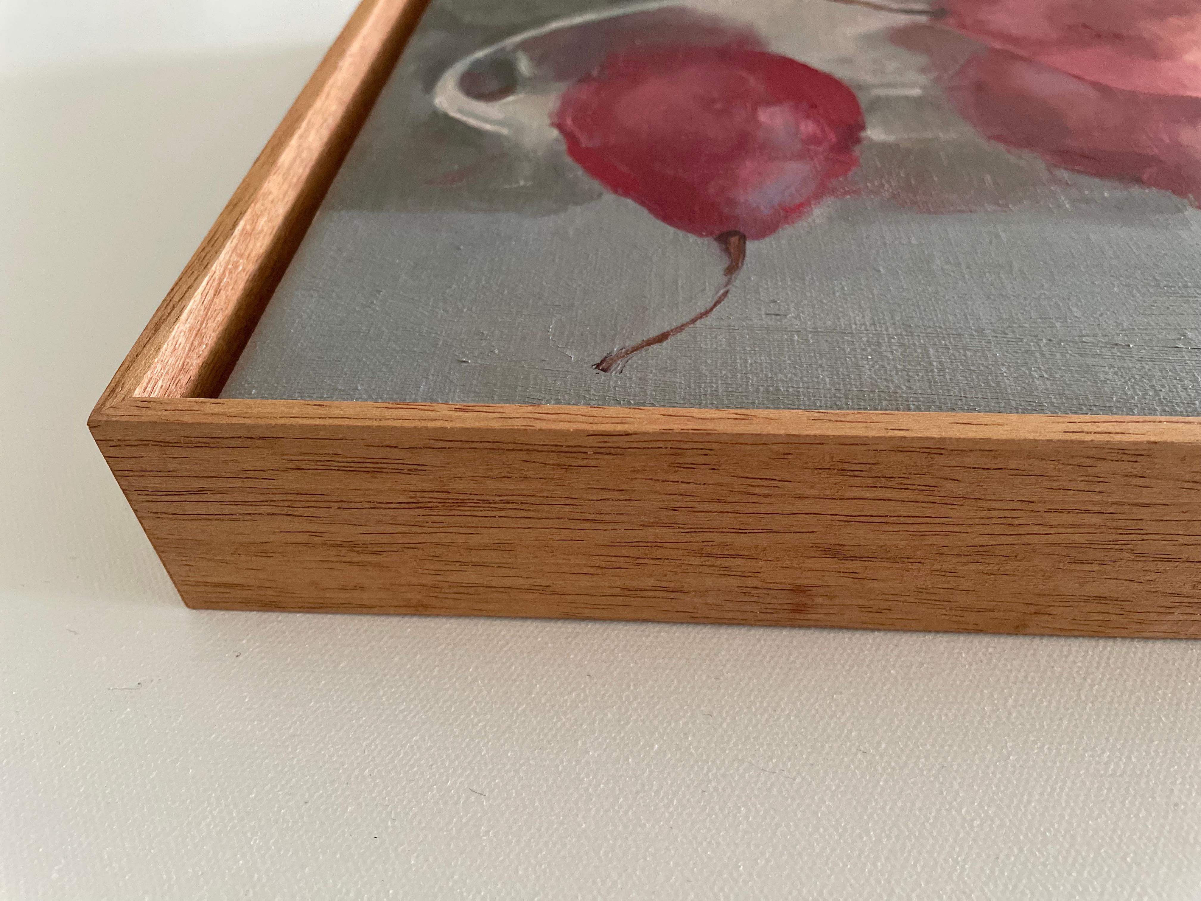 Ölgemälde mit einem einfachen Arrangement aus leuchtend roten Birnen in einer eleganten weißen Keramikschale mit weichen, abgerundeten Griffen. Die Komposition besteht aus einem subtilen Wechselspiel von Licht und Schatten vor einem gedämpften,