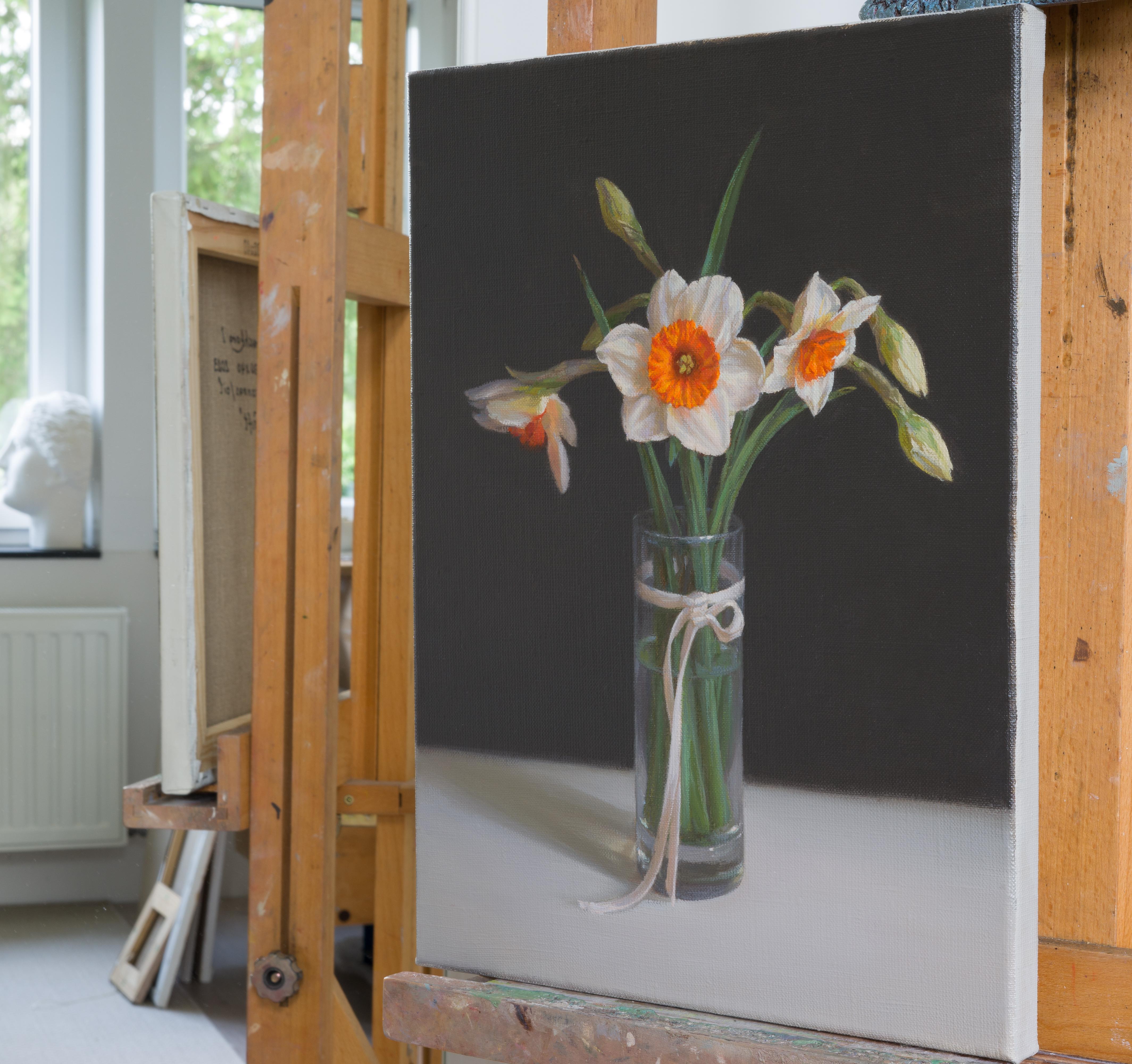 These stunning spring daffodils are placed in a transparent vase and tied with a silk ribbon as a reminder of the gift. A dark background helps to reveal delicate forms of flowers and capture the reactions of light with glass. The painting technique