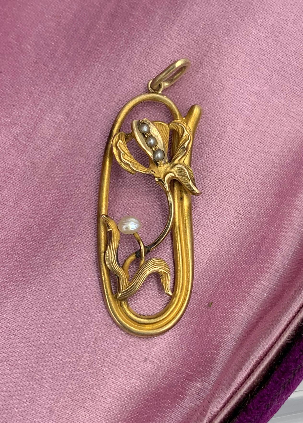 AN ART NOUVEAU PENDANT IN THE FORM OF AN IRIS FLOWER - SO STUNNING WITH THE MOST WONDERFUL THREE DIMENSIONAL DEPICTION OF THE IRIS FLOWER.   THE GOLD WORK IS OF THE HIGHEST QUALITY AND SET WITH SEED PEARL ACCENTS.  THE OPEN WORK DESIGN IS JUST