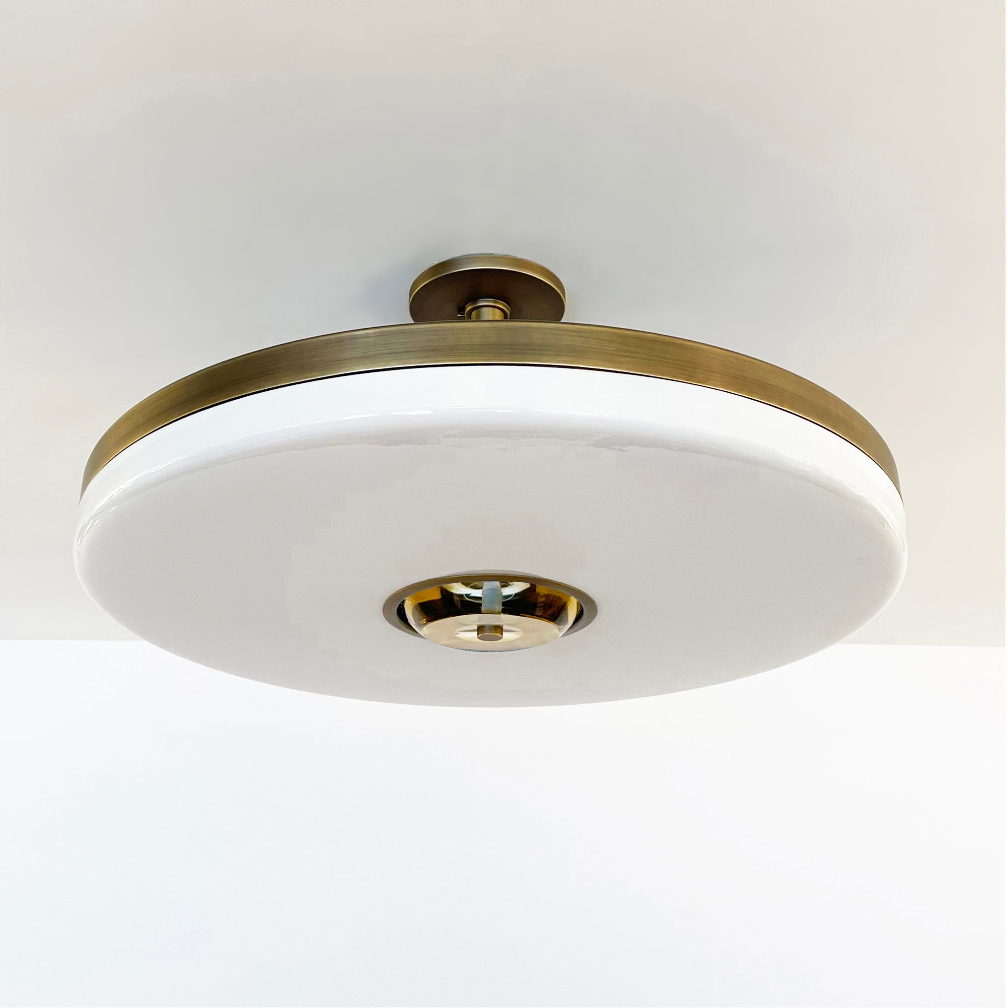 The Iris ceiling is designed around an expansive acrylic shade with a hand carved glass center. This versatile fixture can be installed as a pendant on a stem or as a true flush mount. Shown in our bronzo ottone finish. Price listed for stock model