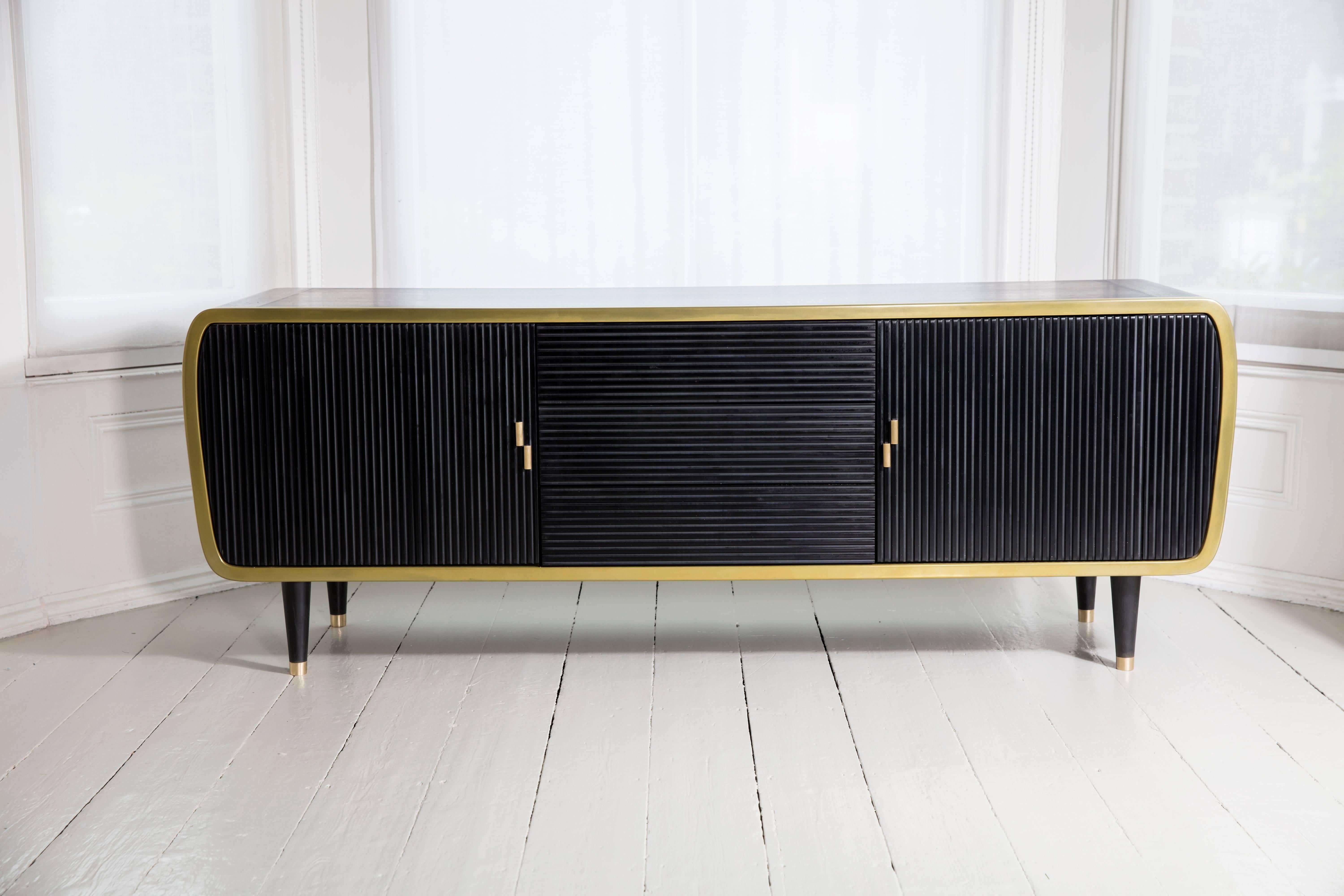This beautiful limited edition piece consists of blackened oak and brass, with drawers lined in suede fabric. A true statement piece! The front is drawers and doors are made of corian with discrete brass handles. The inner cupboards have glass