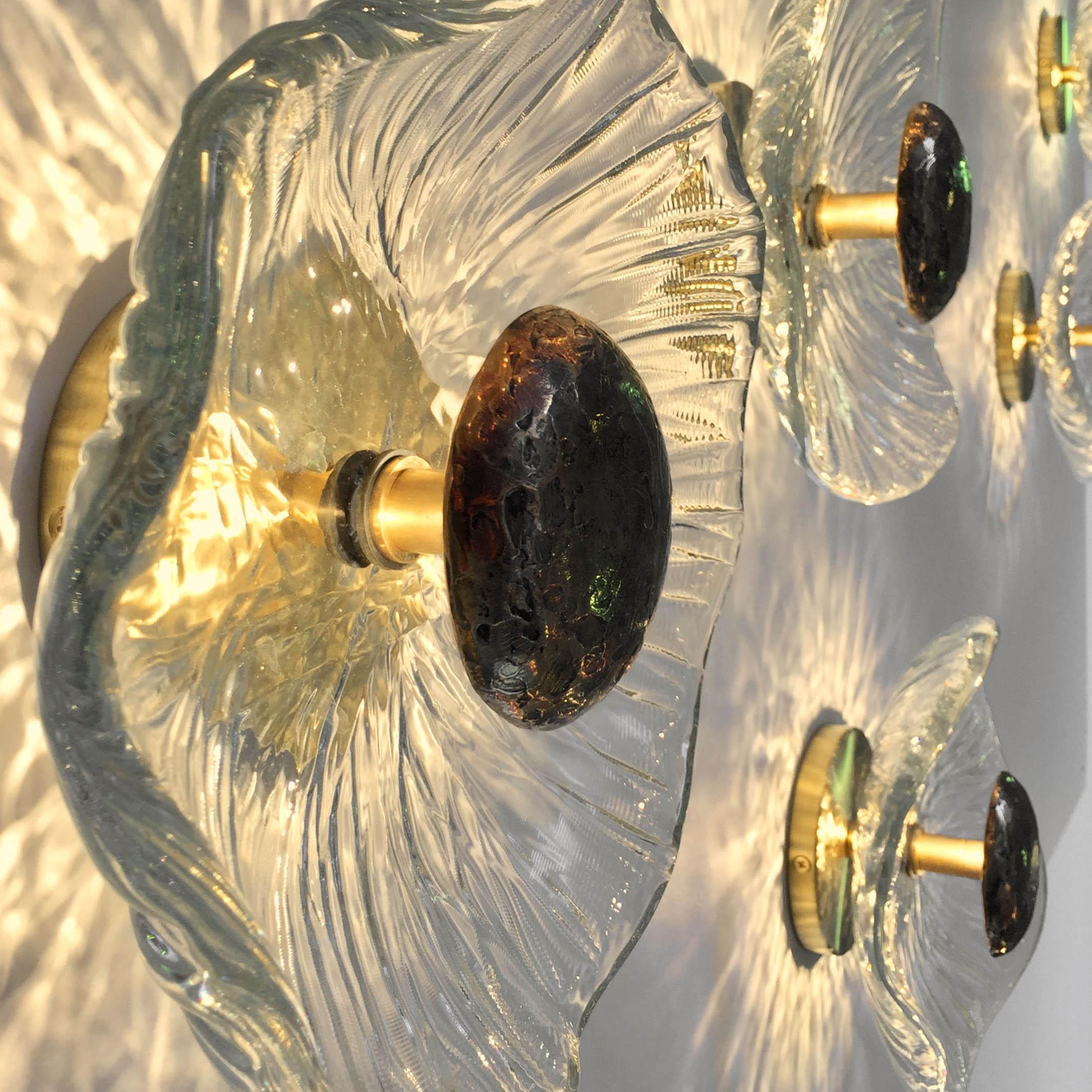 The Iris uses mottled clear thick glass and a cast bronze heat sink to create a fixture that is a combination of ancient crafts and forward thinking. Each glass piece is hand shaped so that the pattern is individual for every one. The molten crystal