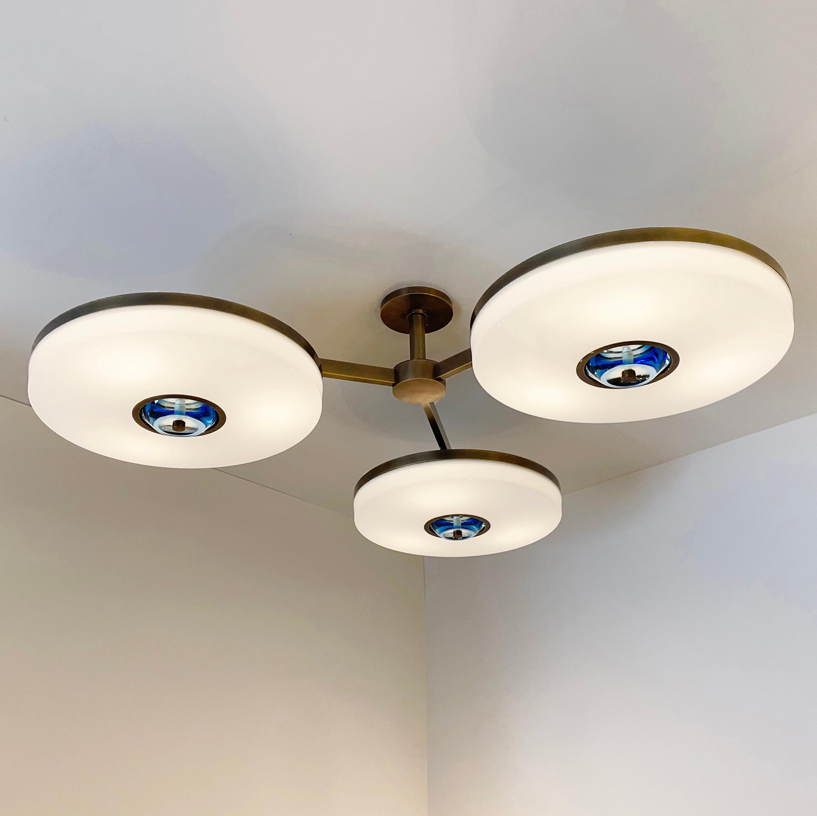 The Iris N.3 ceiling light is designed around three expansive acrylic shades with hand carved glass centers. This versatile fixture can be installed on a stem or as a flush mount. The first images show the fixture in our Bronzo Ottone finish