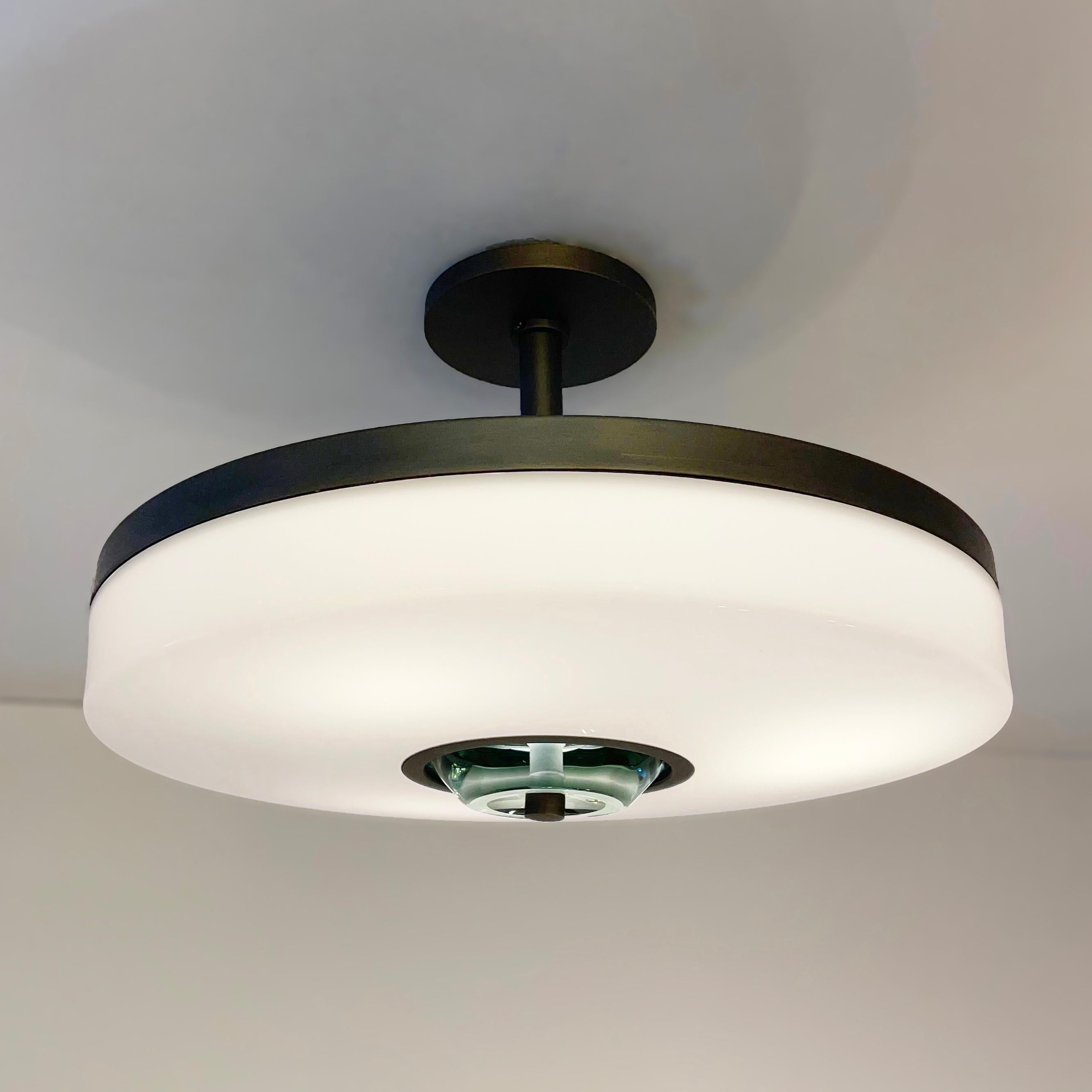 The Iris Piccolo ceiling light is designed around an acrylic shade with a hand carved glass center. This versatile fixture can be installed as a pendant on a stem or as a true flush mount. The first images show the fixture in our Brunito Nero (Black