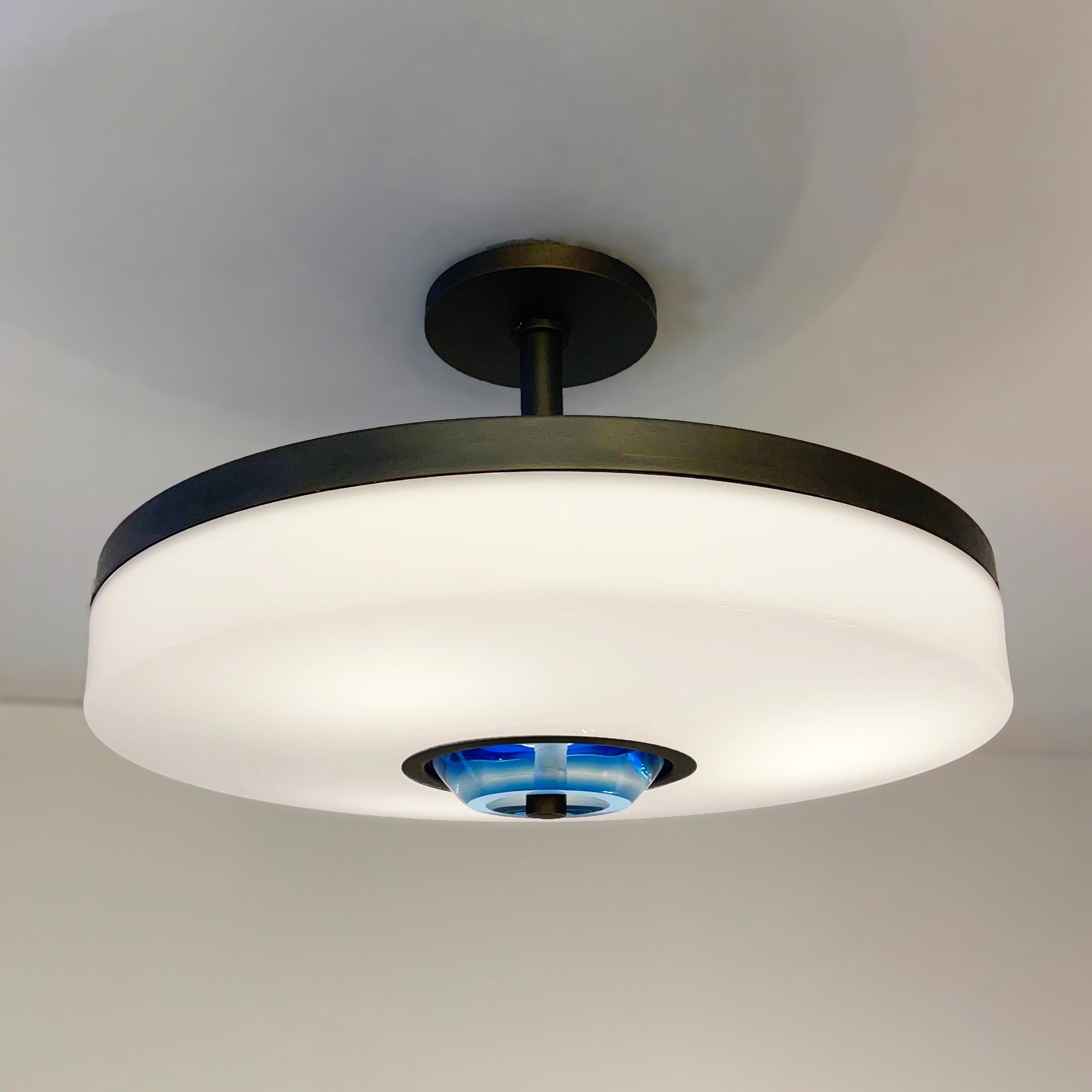 The Iris Piccolo ceiling light is designed around an expansive acrylic shade with a hand carved glass center. This versatile fixture can be installed as a pendant on a stem or as a true flush mount. Shown in our Brunito Nero finish. Price listed for