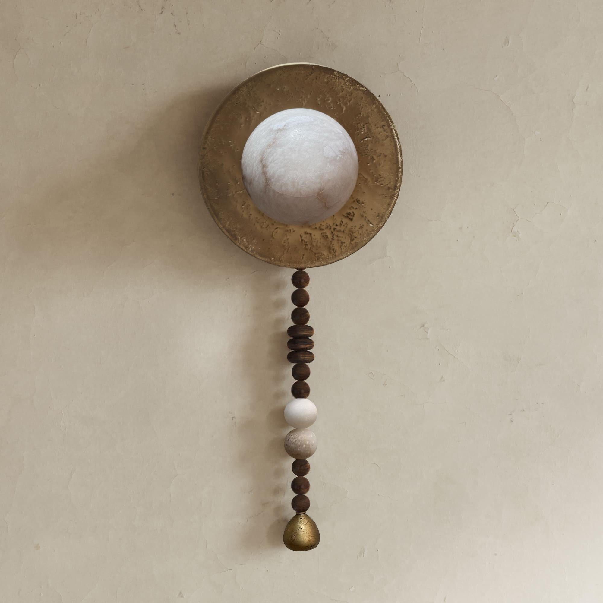 The Iris Wall Sconces a handcrafted lighting fixture, which incorporates solid wood, alabaster and liquid bronze to create a unique appearance. Traditional techniques such as casting and hand sculpting are used in its creation, and each piece is