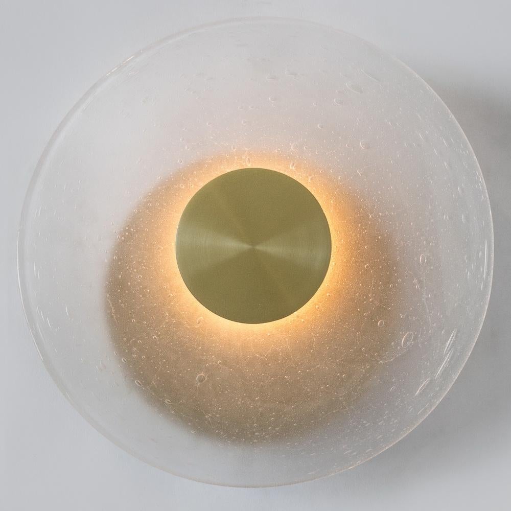 The Iris Wall Sconce is a light fixture made from hand blown glass with an LED light source. The sconces are back-lit with warm white LED strip in the middle of the sconce which radiates outward to create a warm glow. The LED strip is contained by a