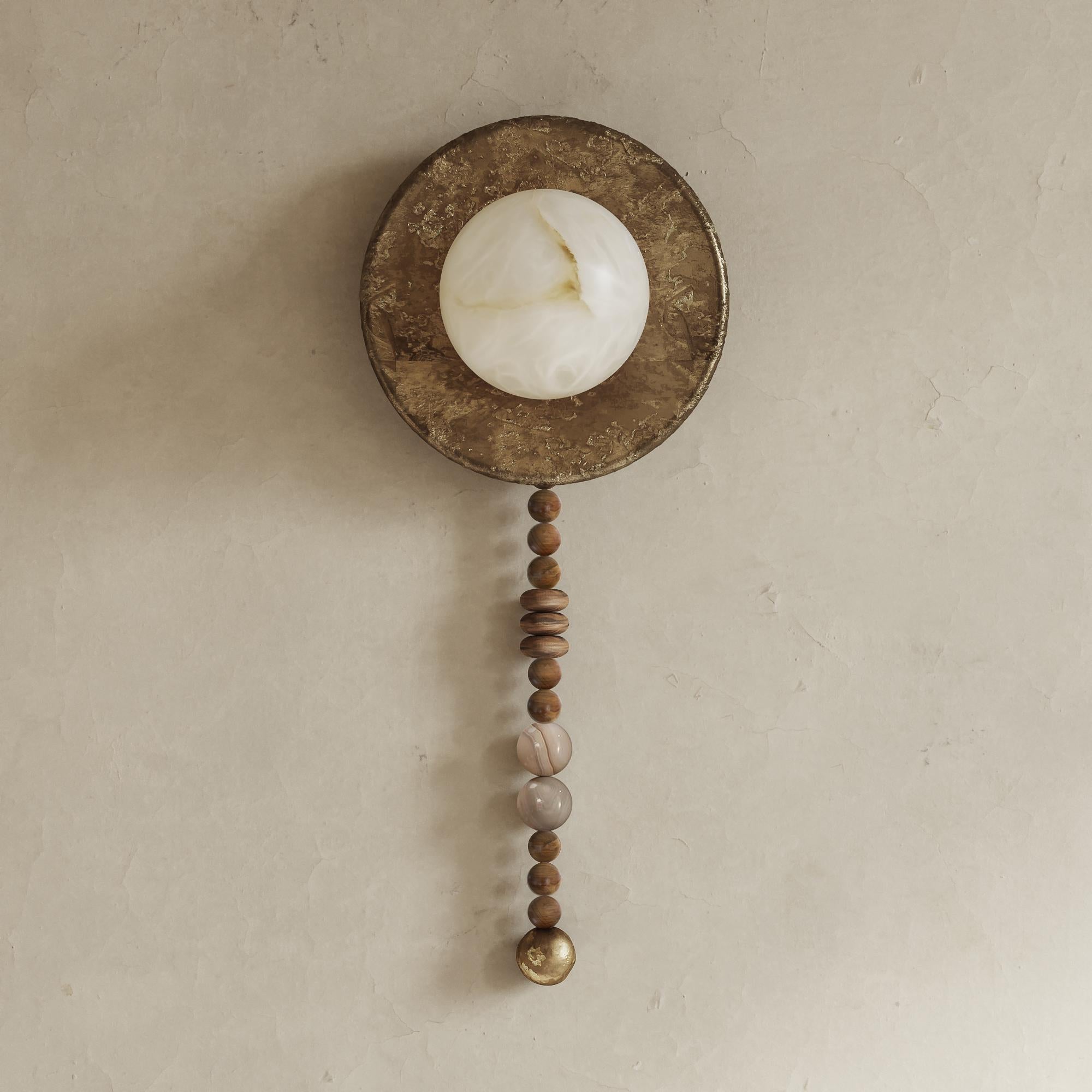 The Iris Wall Sconces a handcrafted lighting fixture, which incorporates solid wood, alabaster and liquid bronze to create a unique appearance. Traditional techniques such as casting and hand sculpting are used in its creation, and each piece is