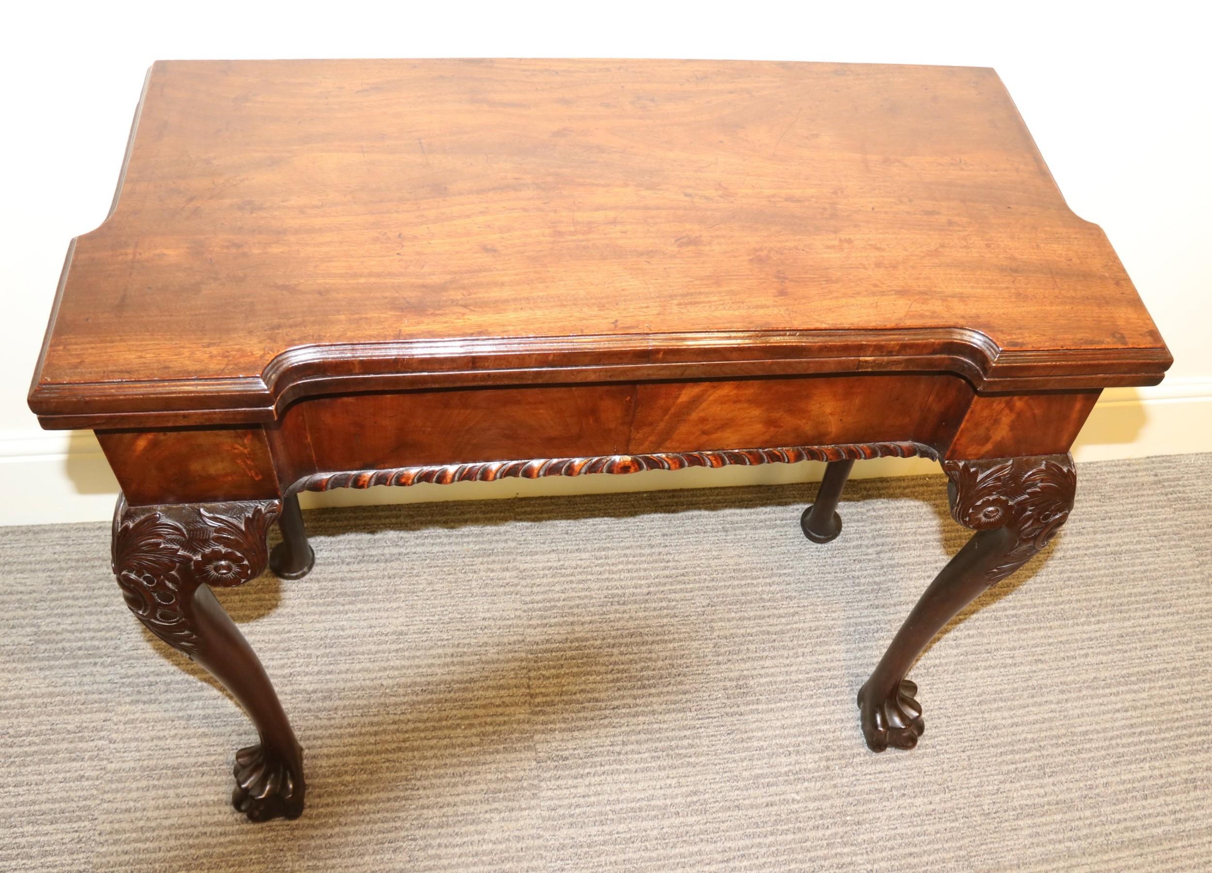 A very good Irish concertina action card table standing on bold carved legs with paw feet, a shaped frieze with a flame mahogany veneer and a figured mahogany top which fold over to reveal a green baized interior with mahogany candle stands,
circa