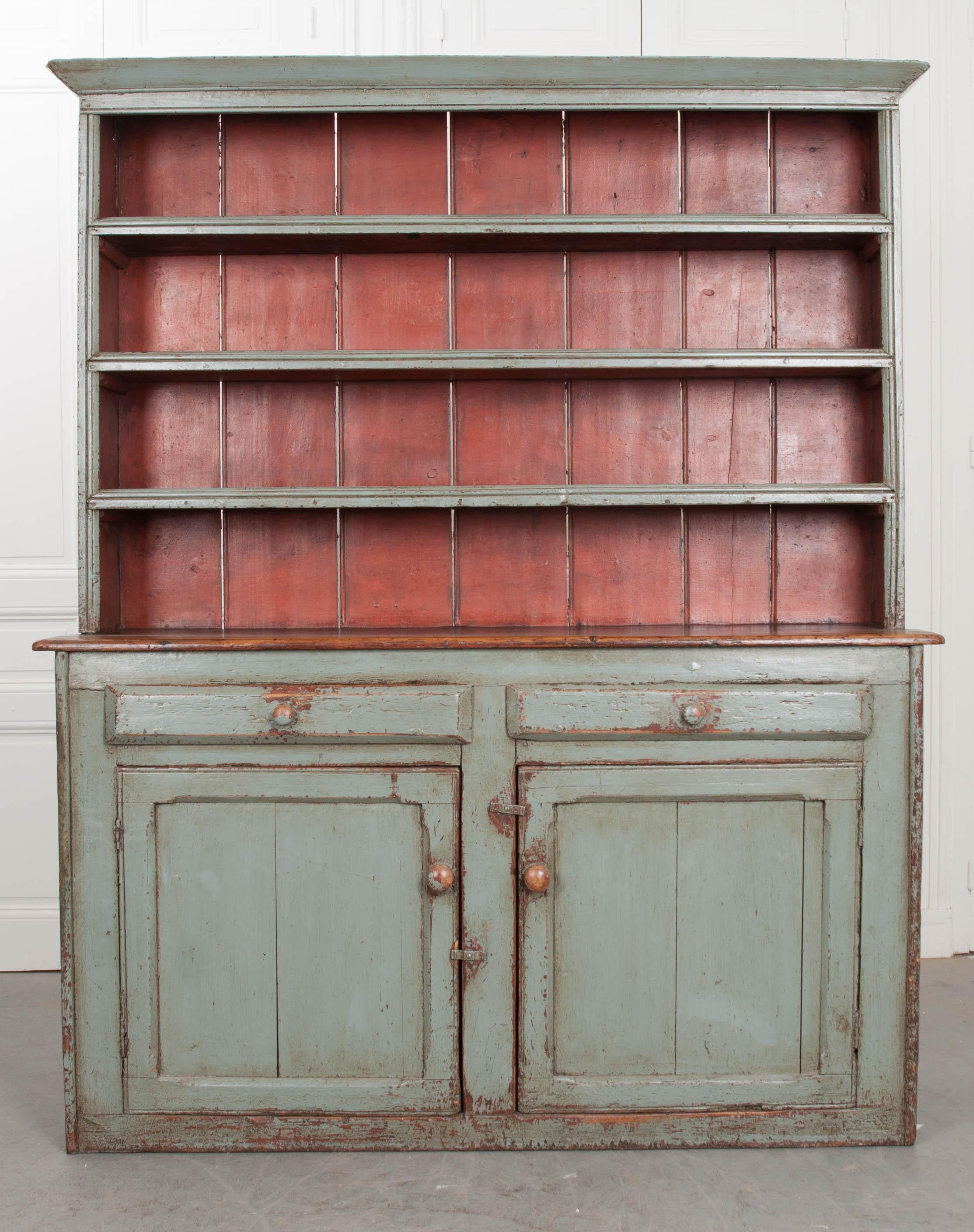 A compelling Irish dresser, with pot board made circa 1840. The polychrome antique is painted a serene teal-green with a red painted pot board backing. The painted finish is exceptionally antiqued and patinated, with natural wood becoming exposed