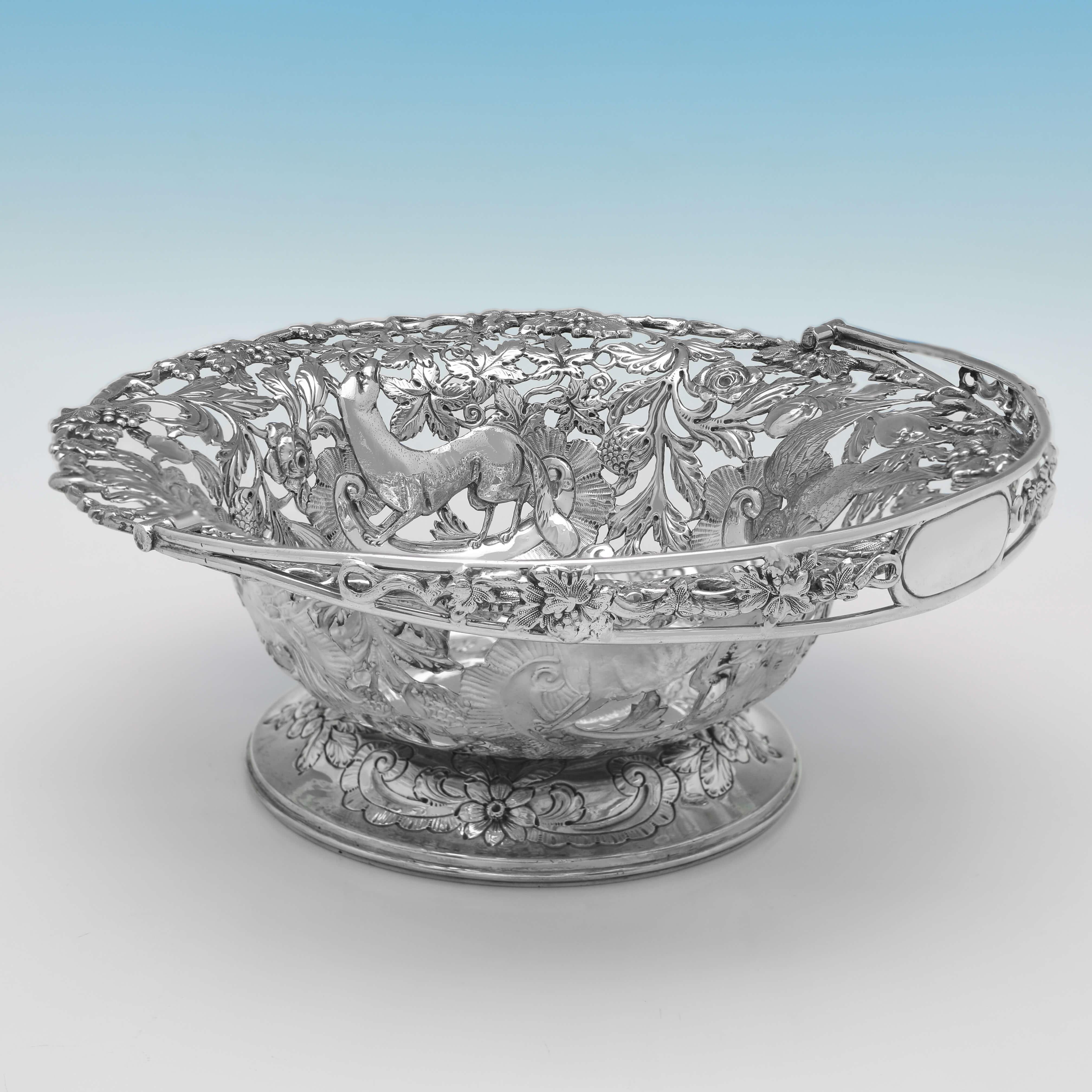 Hallmarked in Dublin in 1911 by Wakely & Wheeler, this striking, Antique Sterling Silver Basket, is round in shape, and features pierced and chased floral and fauna decoration, and a pierced swing handle. 

The basket measures 9