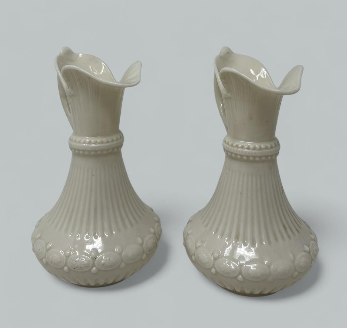 Superbe collection assemblée de deux magnifiques objets décoratifs en porcelaine comprenant une paire d'aiguières ou de pichets Belleek Aberdeen irlandais. 
Toutes les pièces portent la marque noire de la deuxième période (1863-1891). 

Condit :