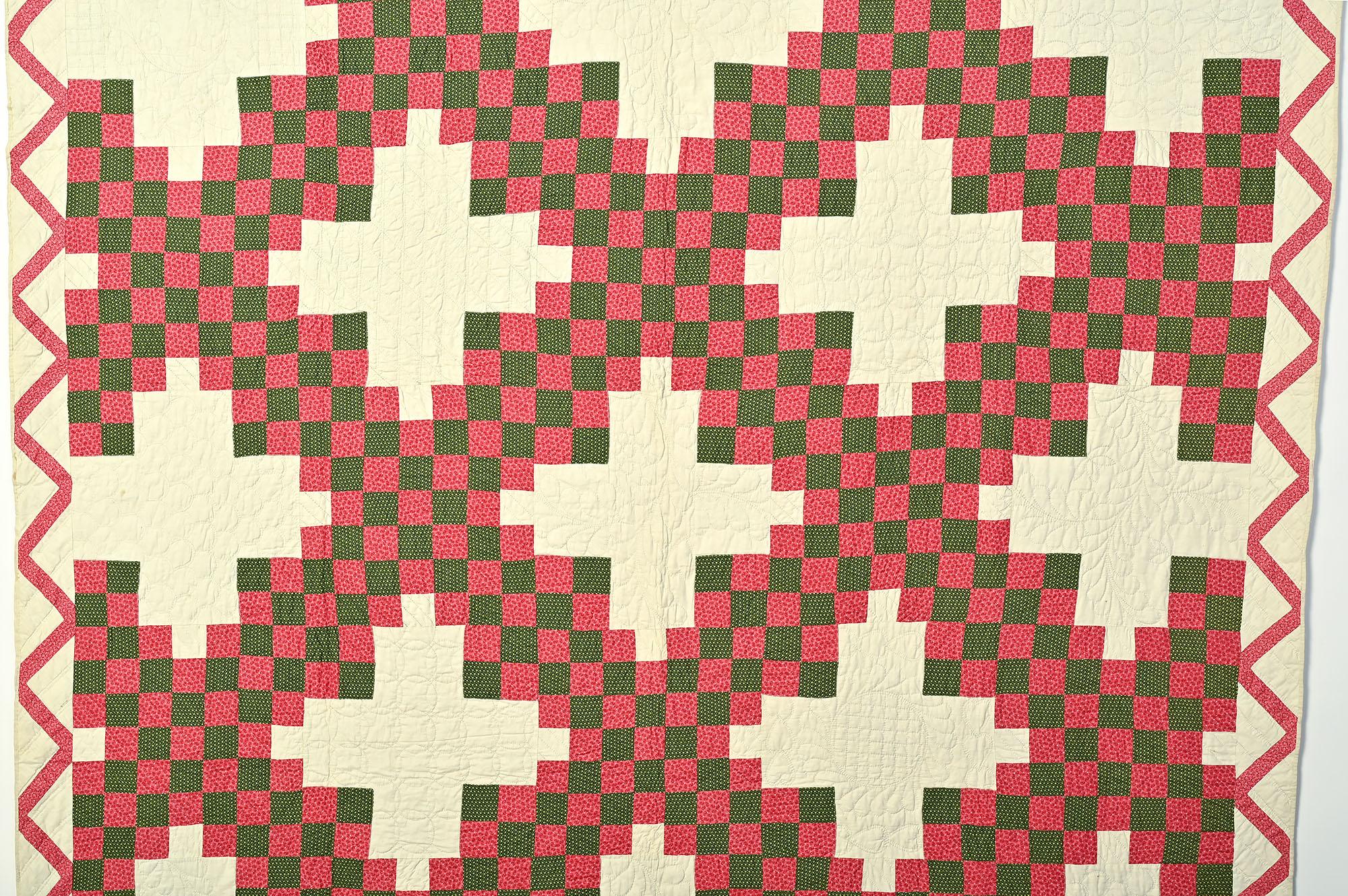 Finely quilted Irish Chain in which the white off blocks are quilted with a variety of patterns that include hearts and feathers. Stitched in two of the blocks are the name Mary and the date 1883 with the 3 backwards. The white background is lighter