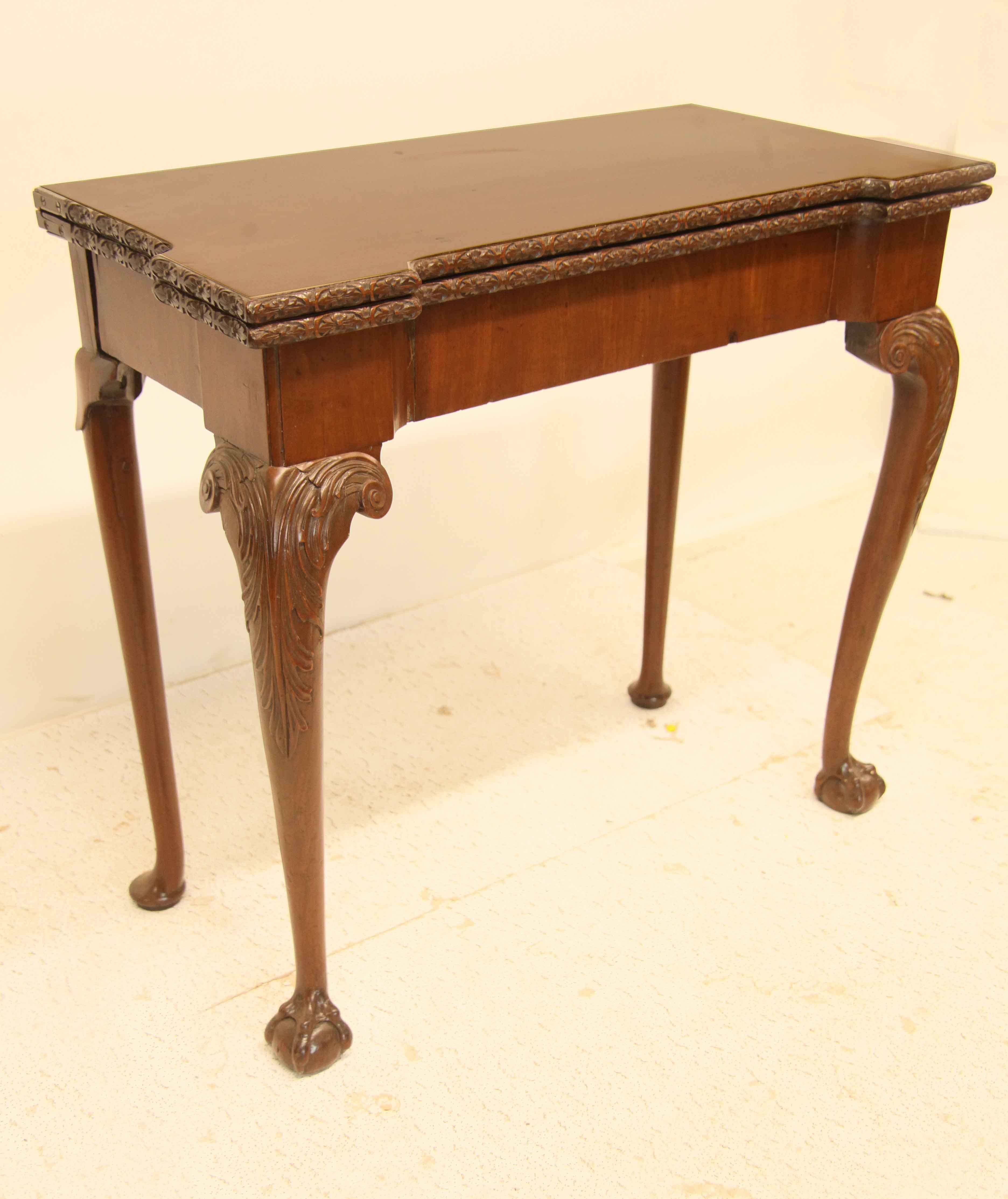 Irish Chippendale game table, beautiful color and patina, the top with carved edge opens up to a solid wood surface, the apron has vertical mahogany veneer, front cabriole legs with elaborate acanthus carved knee and terminates with ball and claw