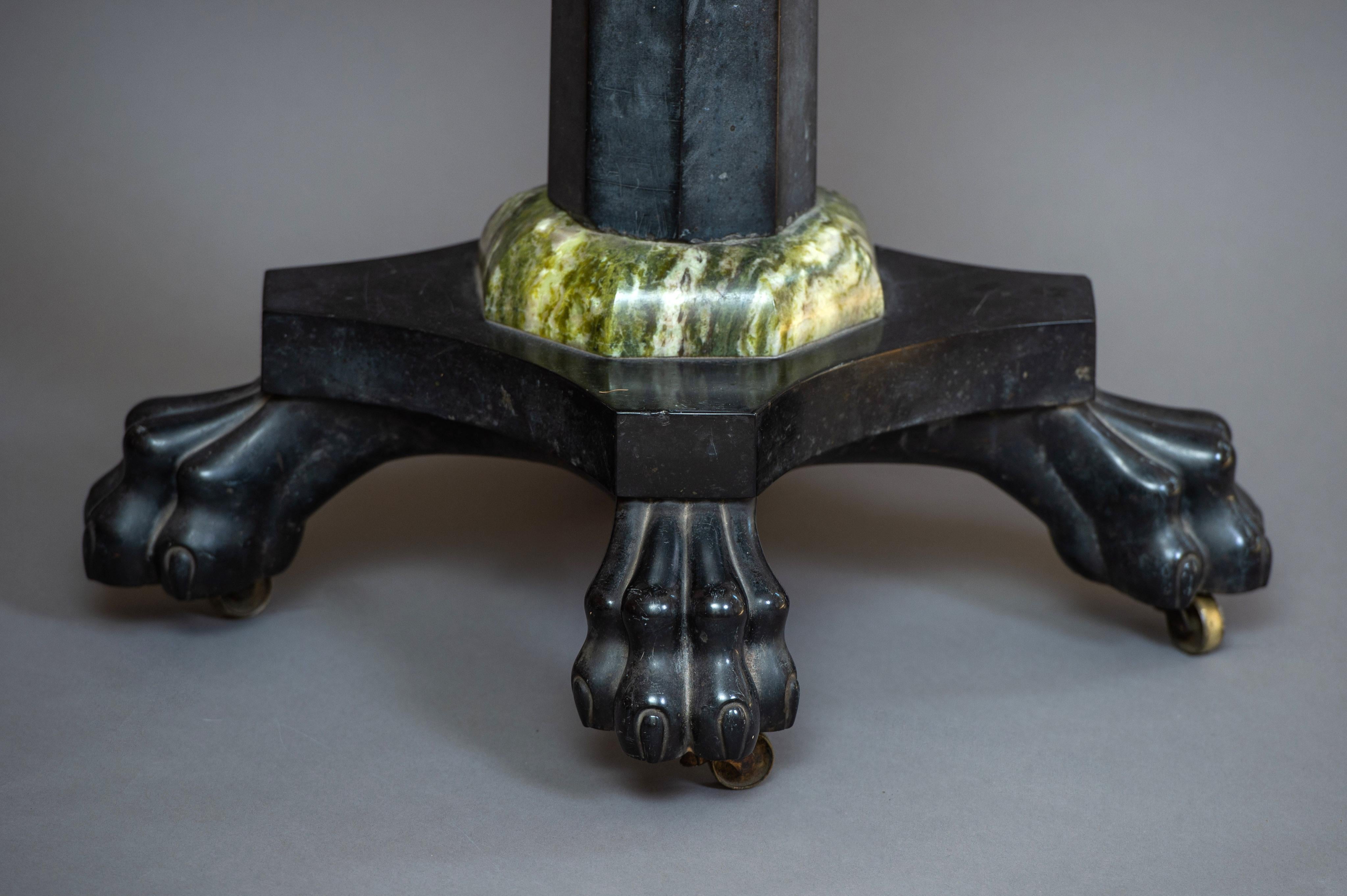 The beautifully figured oval Connemara top is supported on a tapering octagonal column of Kilkenny black marble leading to a quadripartite platform incorporating four carved claw feet on brass castors. The column has finely shaped collars top and