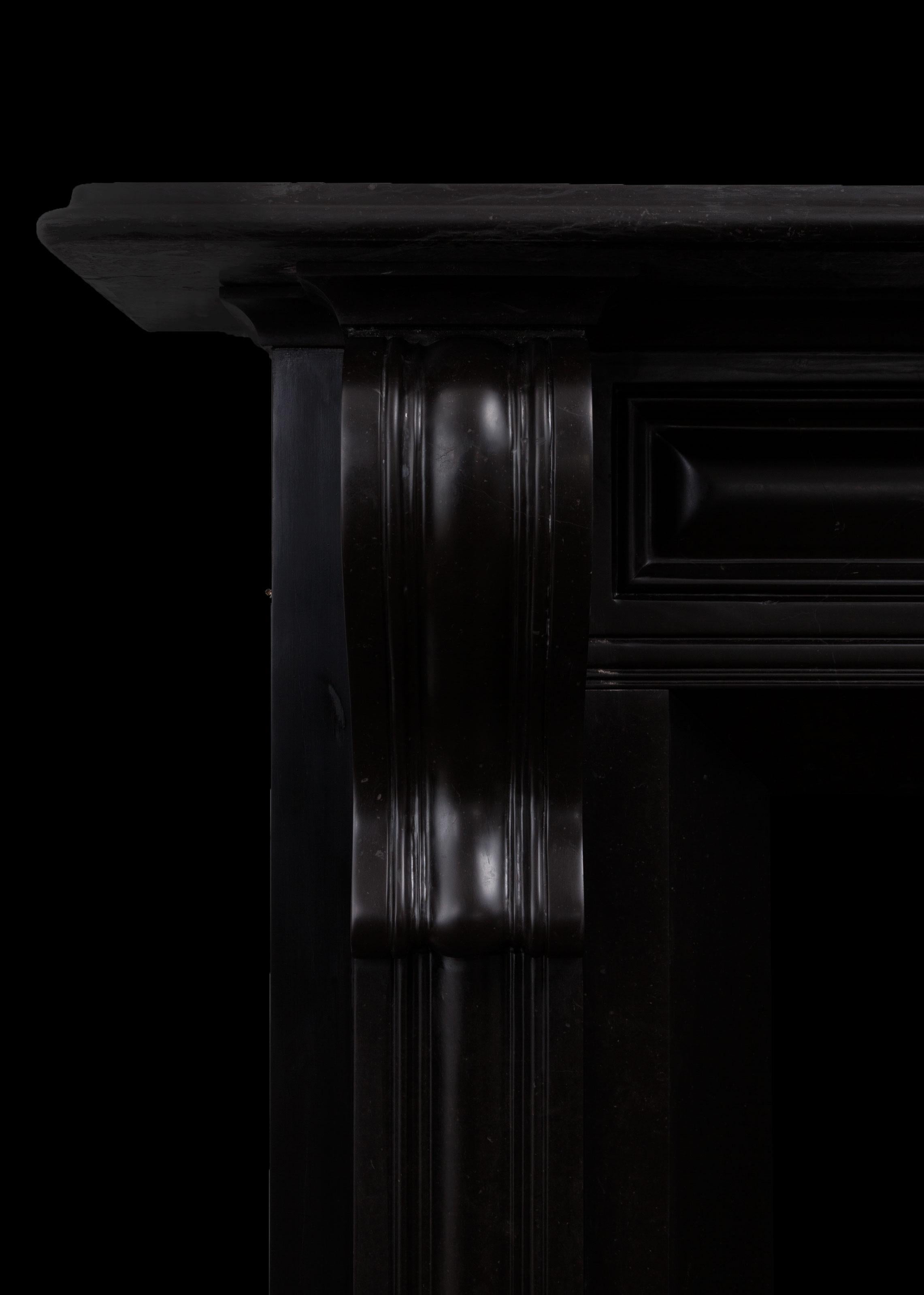 Eine Kamineinfassung aus schwarzem Kilkenny-Marmor.
Dieser Kamin ist im frühen 19. Jahrhundert im irischen Regency-Stil gehalten. Er hat gepolsterte, in Kragsteinen auslaufende Platten, eine sich verjüngende Öffnung und eine tiefe, geformte Ablage.