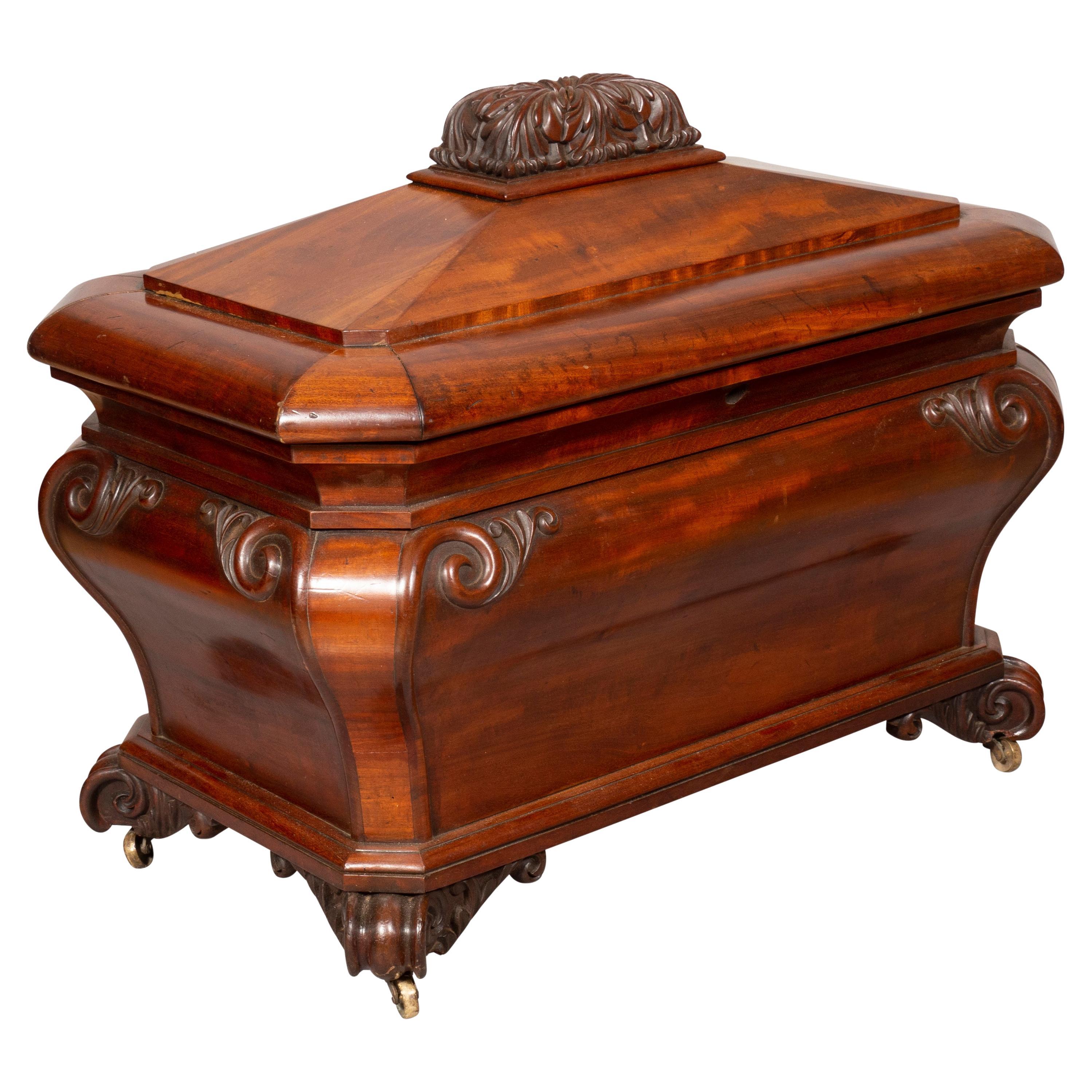 Rectangular hinged and domed top with carved finial opening to a well , lower conforming serpentine bombe case with scroll carved corners, carved scroll feet. Casters.