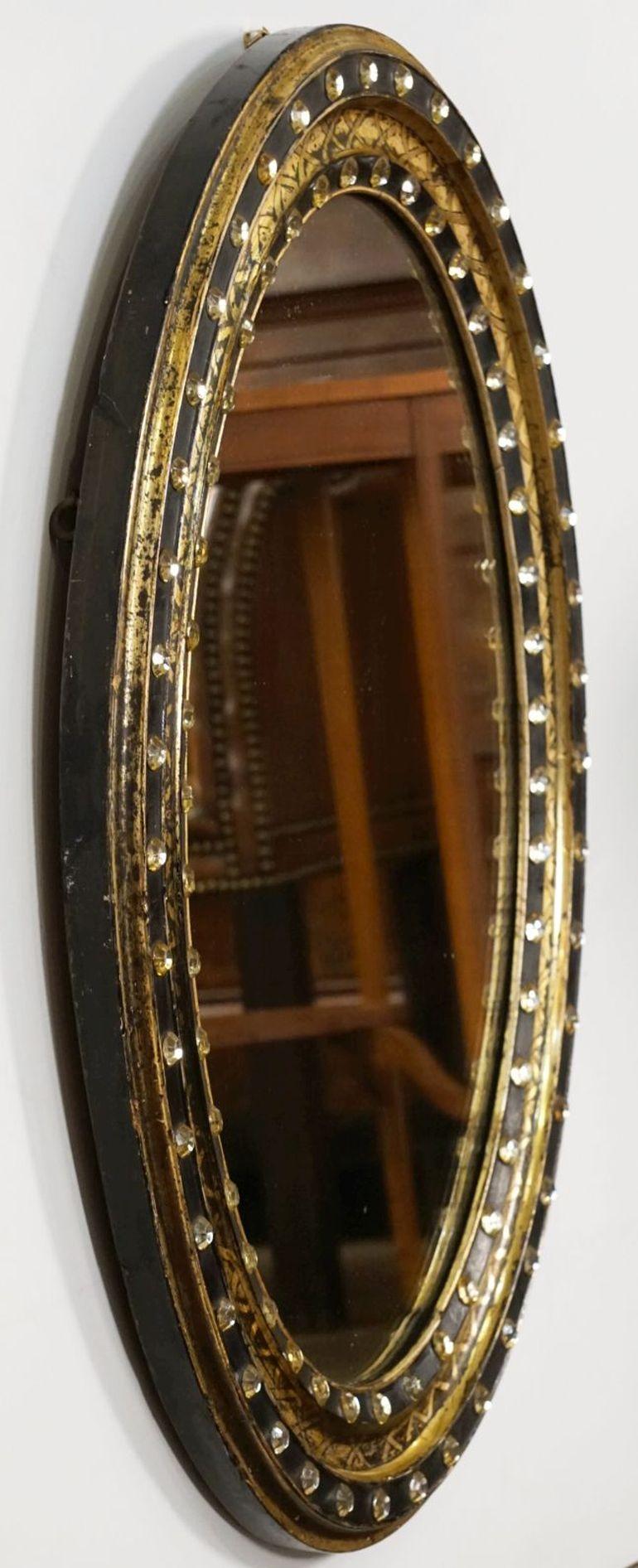 A fine Irish oval wall mirror from the 19th century, featuring a distinctive frame of alternating raised ebonized slips with original faceted glass stud decorations (Waterford border beads), separated by gilded and X-decorated recesses. 

Measures: