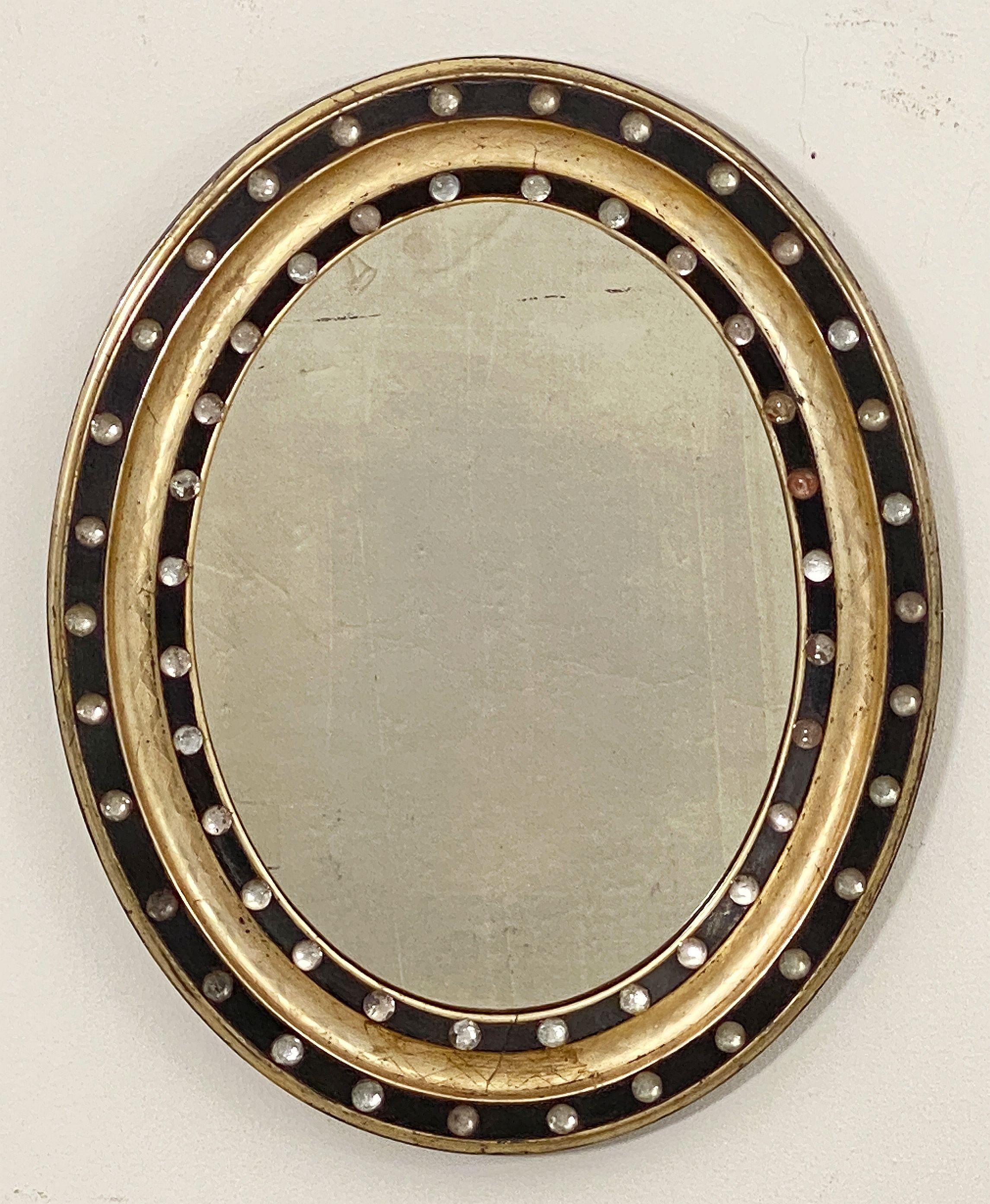 A fine Irish oval wall mirror from the 19th century, featuring a distinctive frame of alternating raised ebonized slips with original glass stud decorations (Waterford border beads), separated by gilded and etched recesses.

Measures: H 21 in x W 16