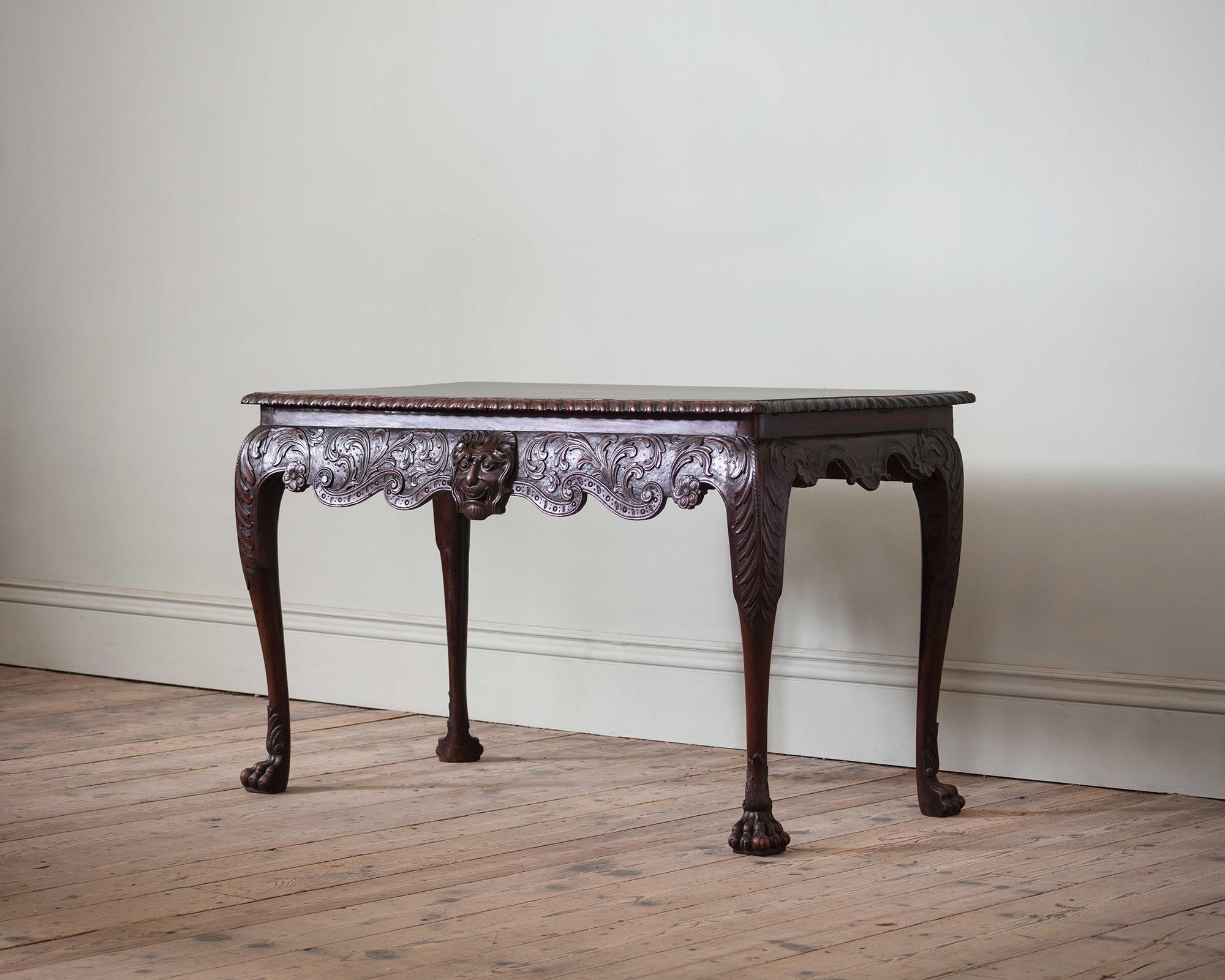 Mesa auxiliar irlandesa de caoba de Jorge II

La parte superior rectangular con borde estriado, sobre un friso tallado con follaje en volutas centrado por una máscara de león tallada con carácter y seguridad, sobre patas cabriolé con pies de