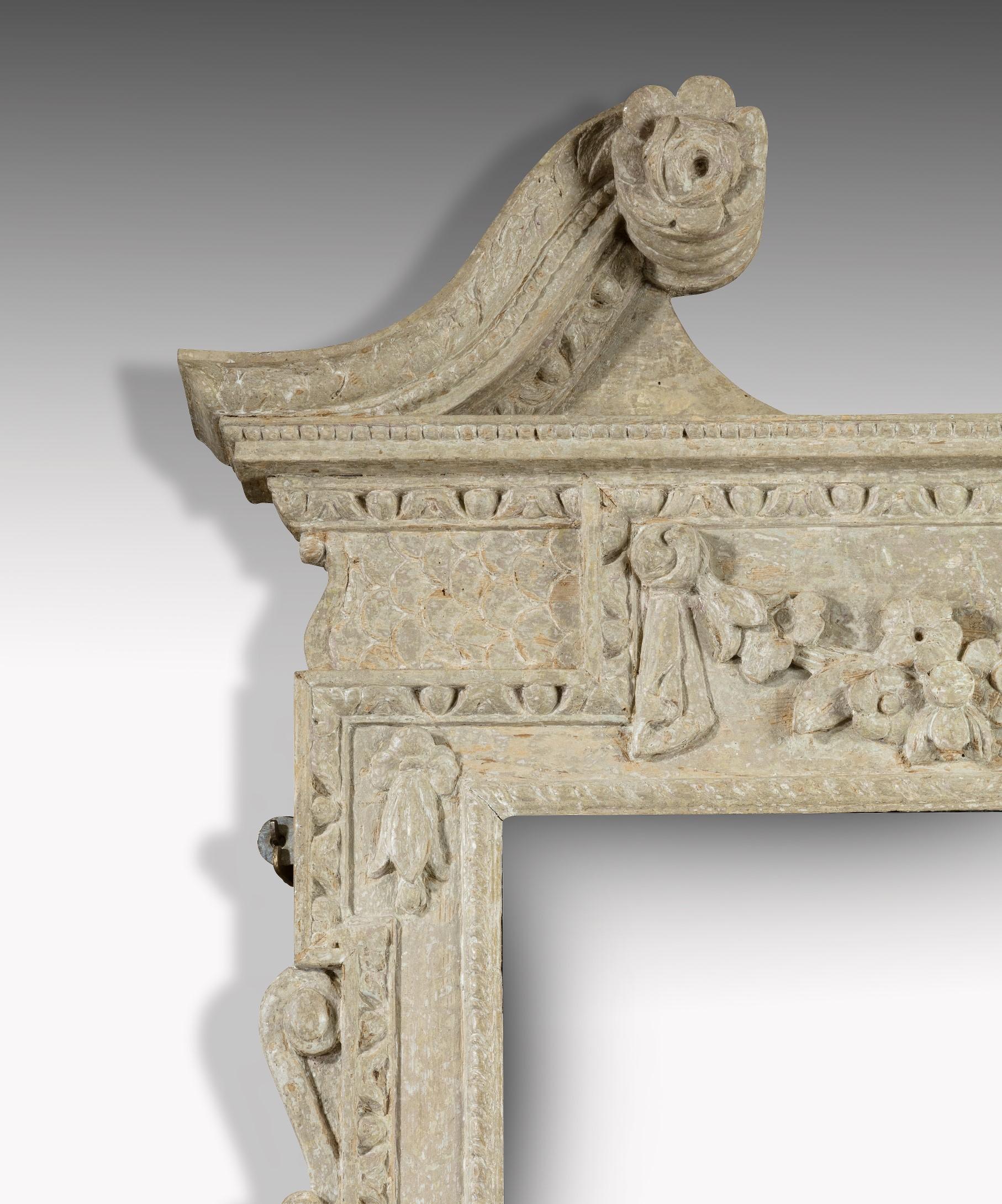 A rare Irish George II mirror in the Kentian style, the mirror plate set within a carved and painted frame which is surmounted by a swan neck pediment above an entablature carved with a swag of flowers. The mirror's apron is carved with a central