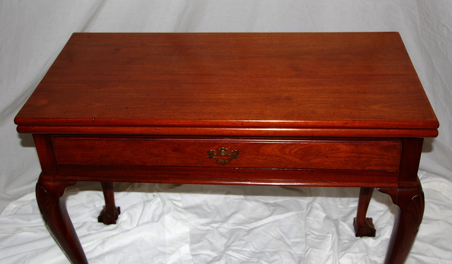 Irish George II period Chippendale mahogany fold over tea table with shell carved knees, cabriole legs and carved ball and claw feet. This tea table also has a drawer, which is unusual in this form. The top has had a repair and the gate has been
