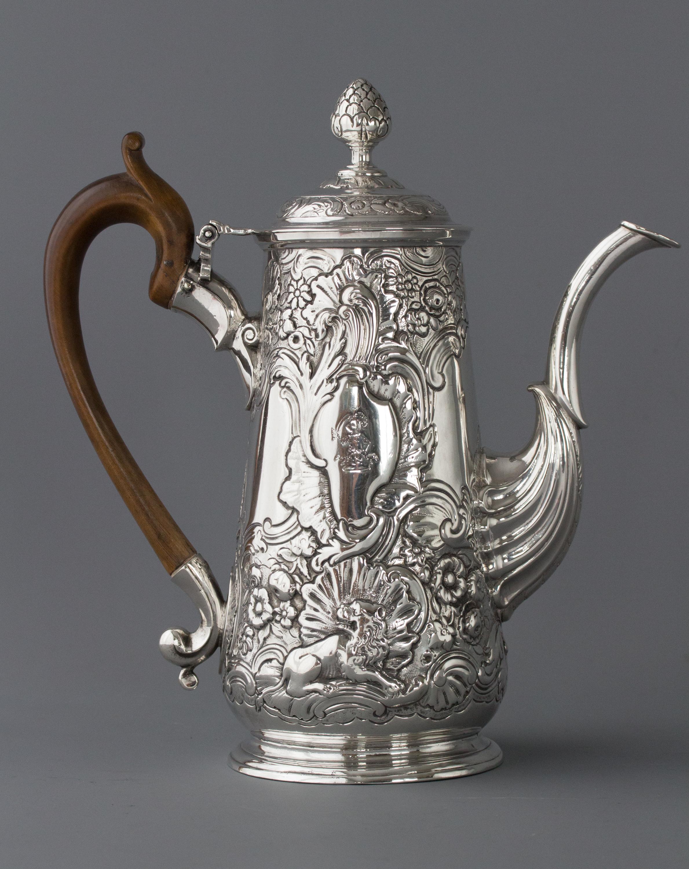 An exceptional quality Irish George II silver coffee pot. Of tapering baluster form with high embossed and chased decoration of lion and eagle with floral and scroll patterns above. Cast leaf-capped spout, a high raised floral decorated band to the