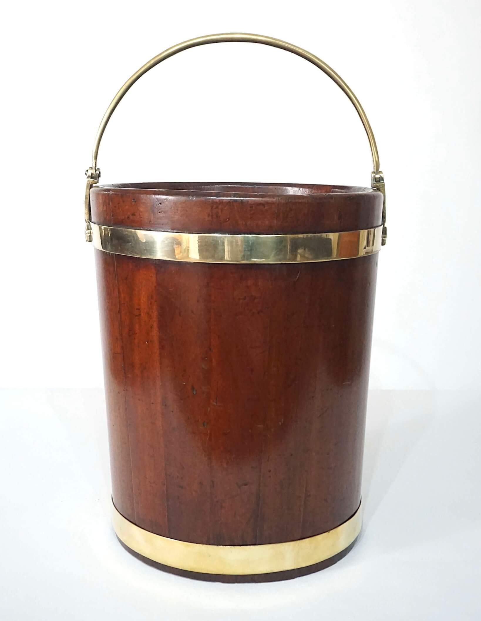 A wonderful large Irish George III circa 1780 peat, turf, or kindling bucket of solid mahogany stave construction and round tapering form with brass banding and pivoting handle, Edwardian period tin liner marked by maker 