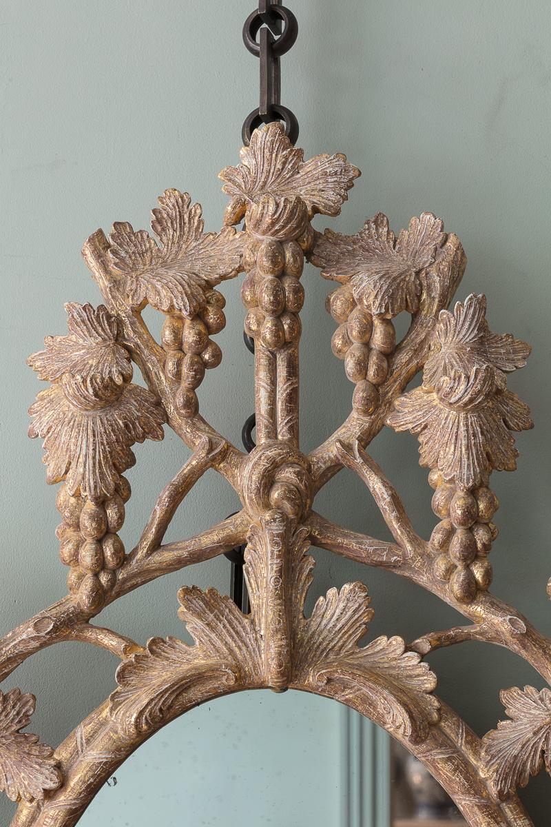An Irish George III Giltwood Mirror, attributed to John and Francis Booker, Essex Bridge, Dubin

With intricately carved branches and vine leaves, with large bunches of loosely hanging grapes, with a central tied ribbon apron, and clear mercury