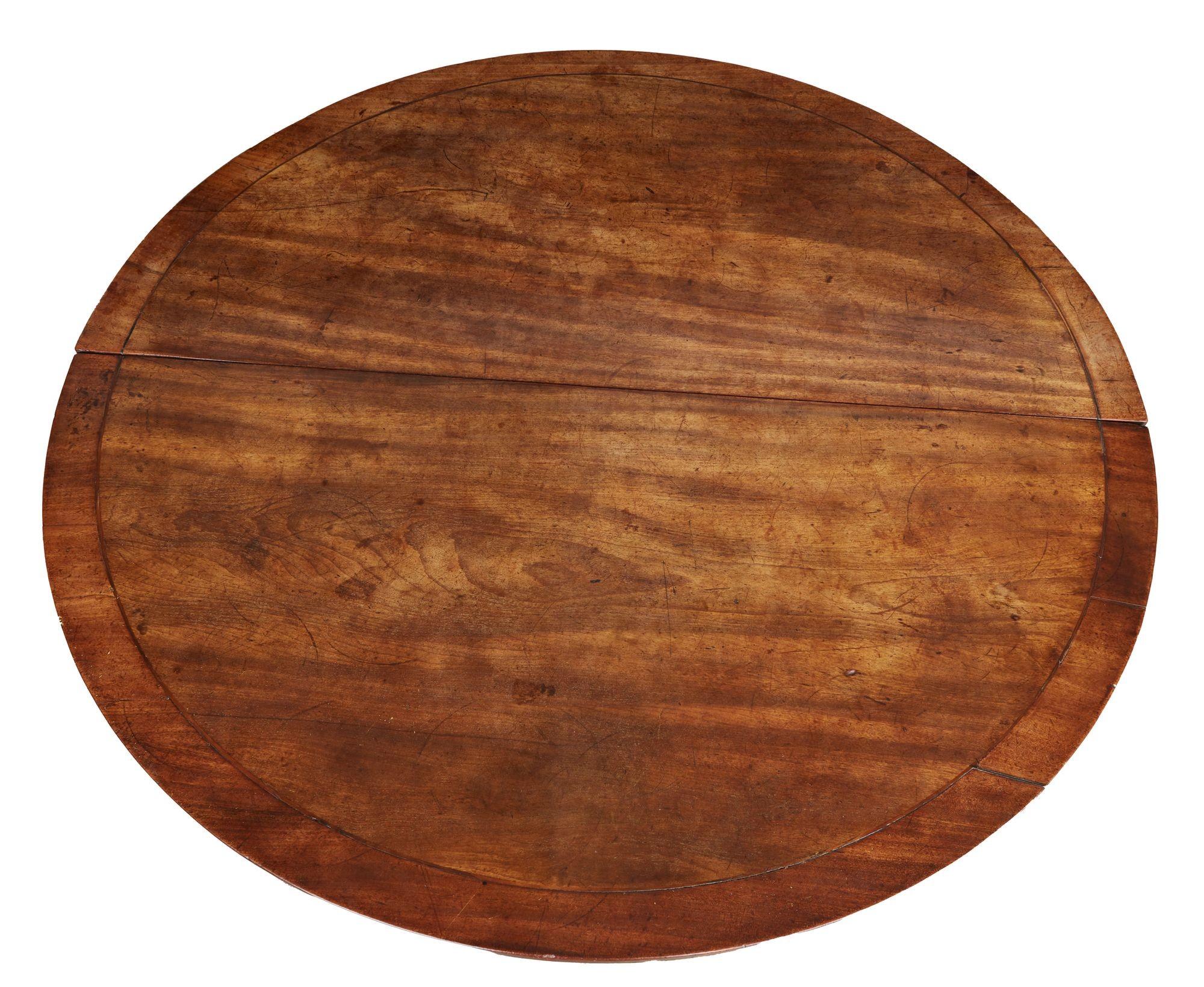Irish Georgian circular center or breakfast table in vividly grained mahogany with a banded and string inlaid border, the divided top consisting of two halves, one of which swings down on a detaching hinge mechanism for storage or display.  On four