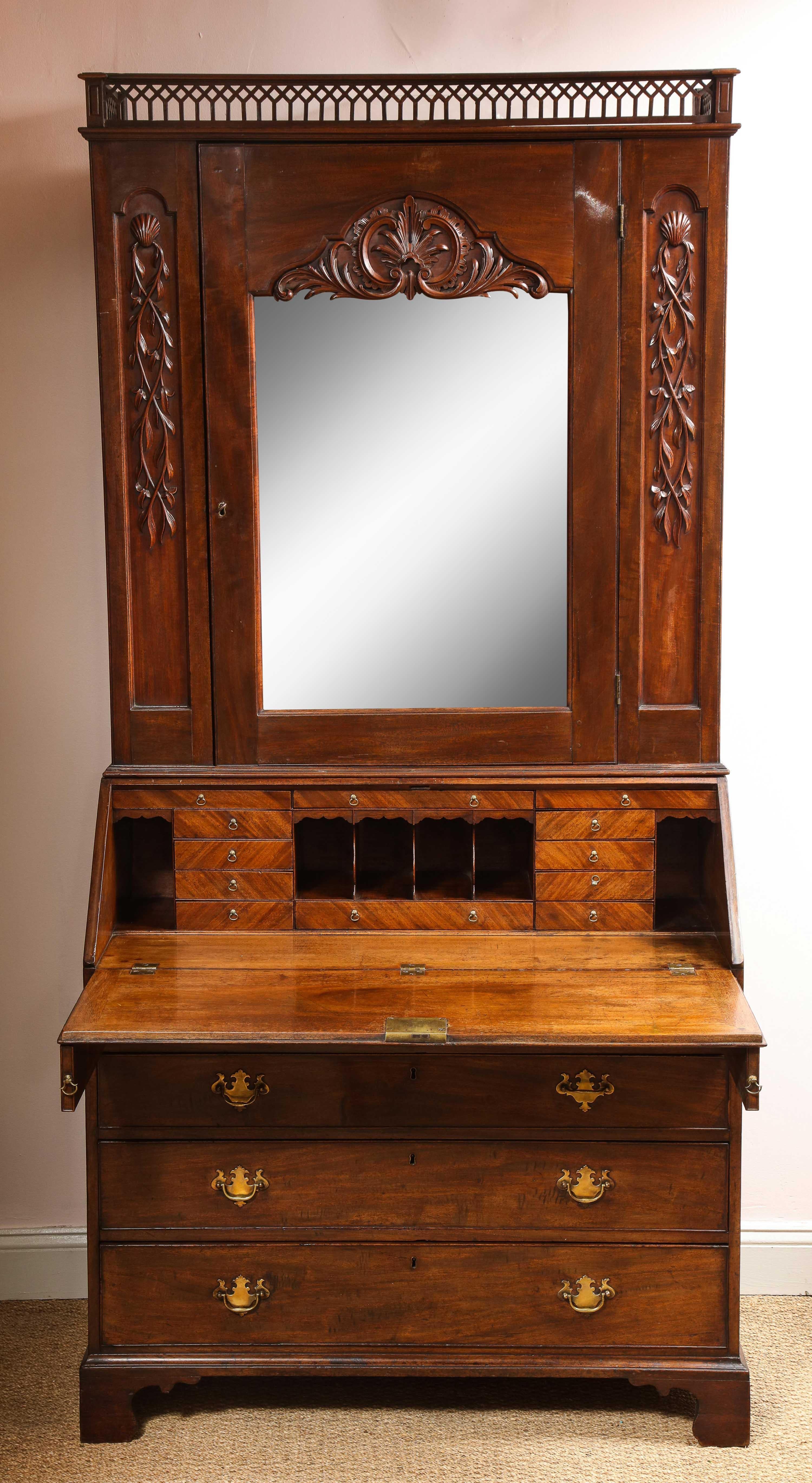Fine and unusual 18th century Irish mahogany bureau bookcase, the pierced gallery top with Gothic details, the pilasters and door with rich and crisply carved shell and foliate design, the door with original beveled mercury glass mirror, over fitted