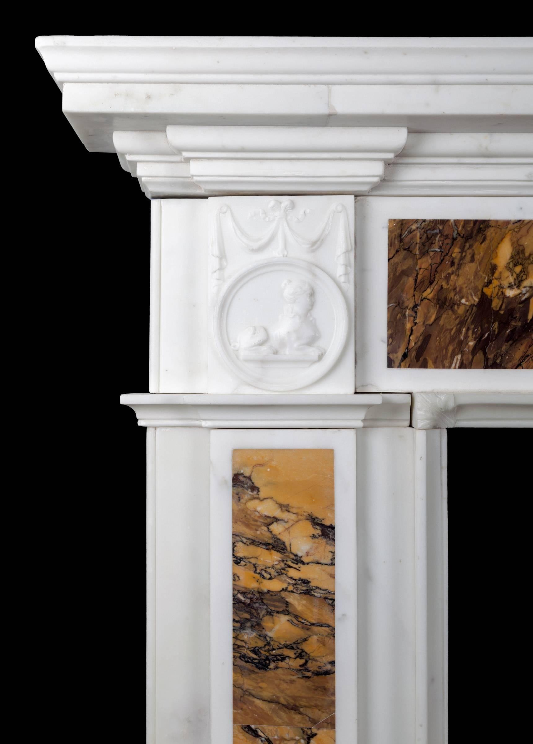 Superb quality Irish George III neoclassical marble fireplace. Made from pure white Italian statuary Carrara marble, inlaid with richly coloured convent Sienna marble. The corner blocks of circular medallions with sphinxes in the centres, these