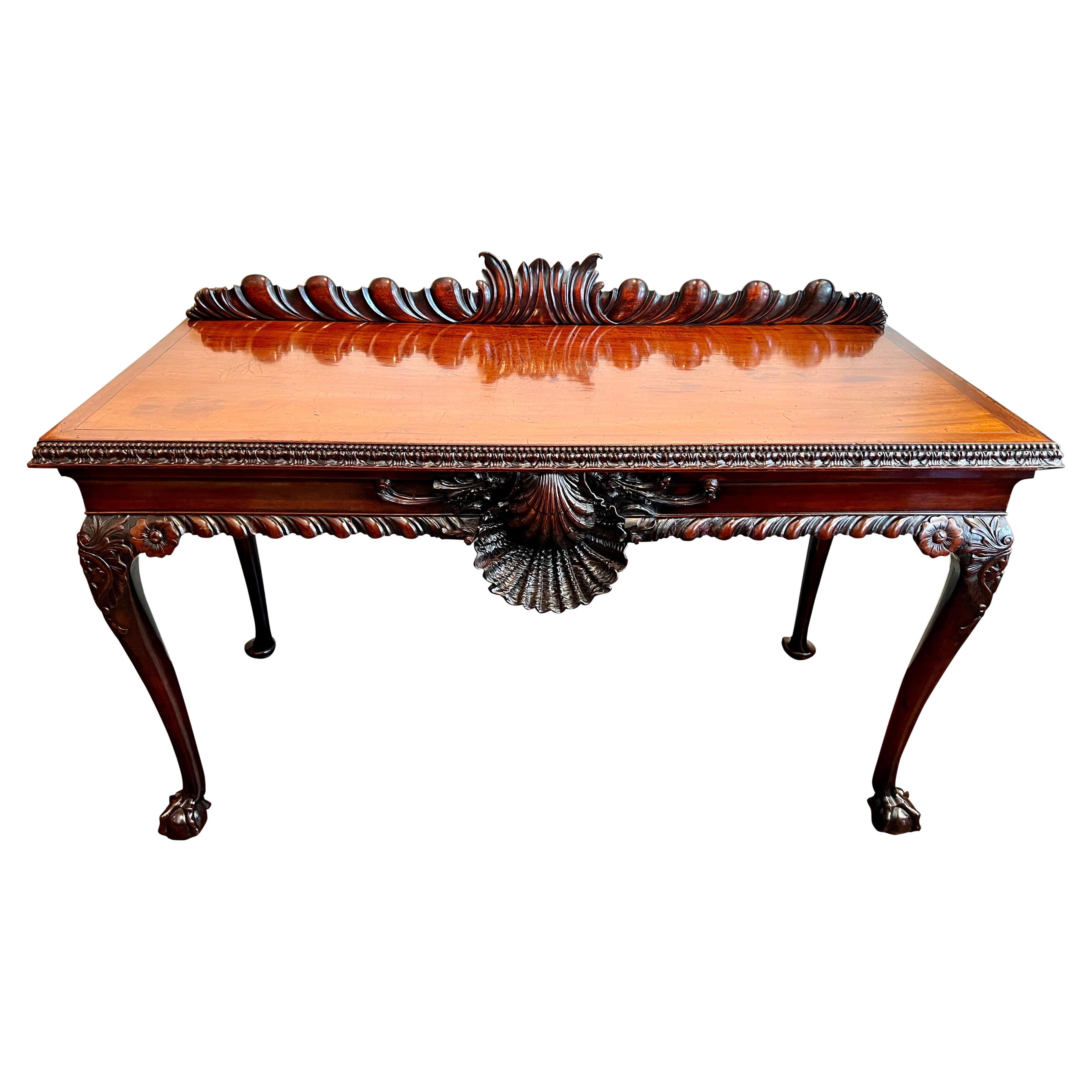 An extraordinary highly carved Irish mahogany serving table from the Chippendale period, the top surmounted with a fluted and carved backsplash, the front edge gadrooned, beaded and centered by a dynamic beautifully carved shell. The piece is