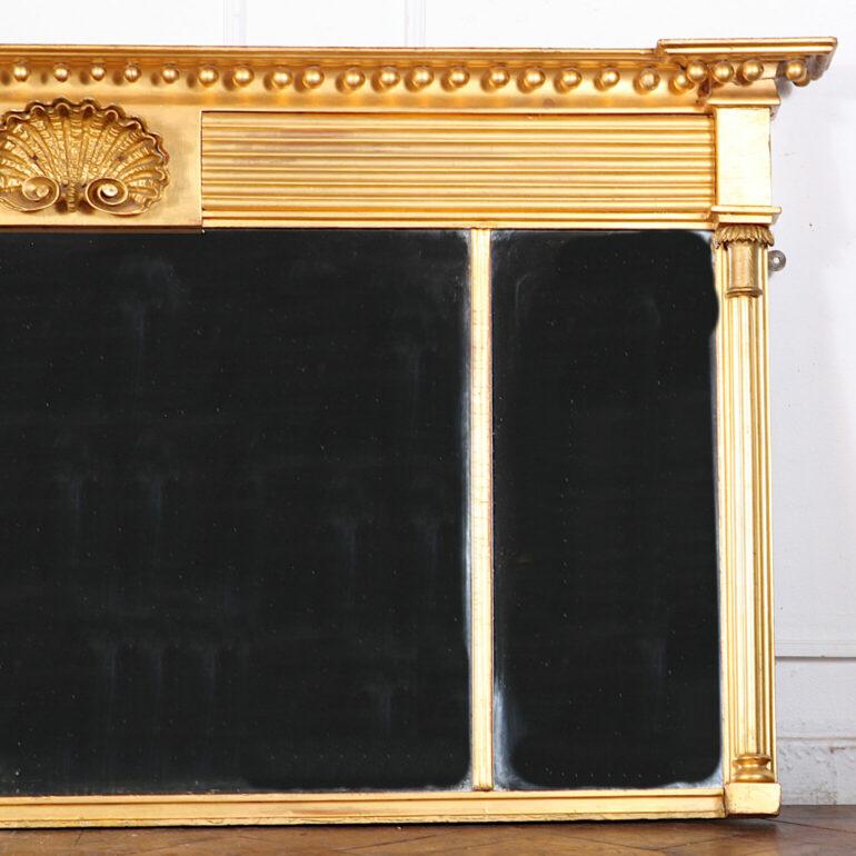 Unusual Irish mid-19th century three-panel neo-classical carved and gilt over-mantle mirror, the frame with broad molded cornice and central shell motif and with fluted pilasters flanking the glass on each side. 



