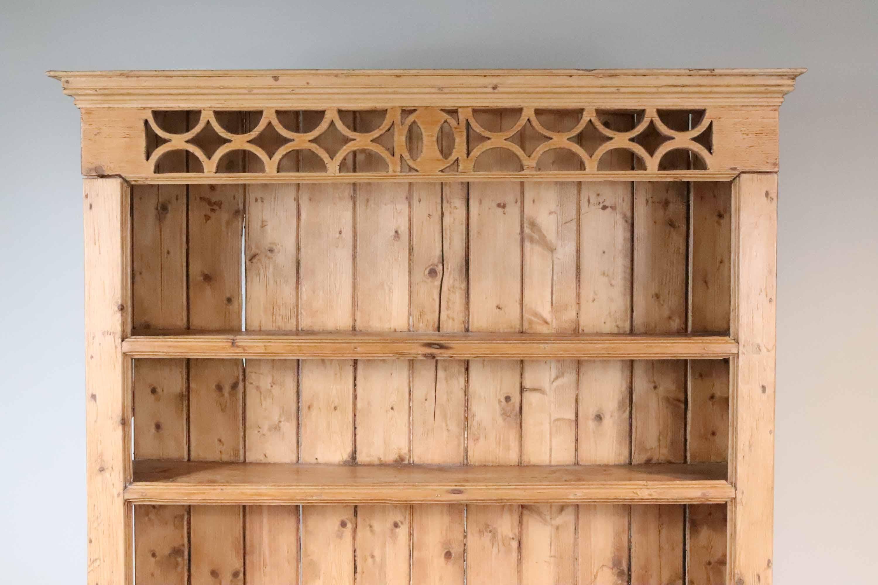 A charming Irish country scrubbed pine step-back cupboard with open shelves above a lower cabinet with two drawers and two doors, mid 19th century. Interesting open fretwork detail above the shelves. The piece is one section, does not come apart.