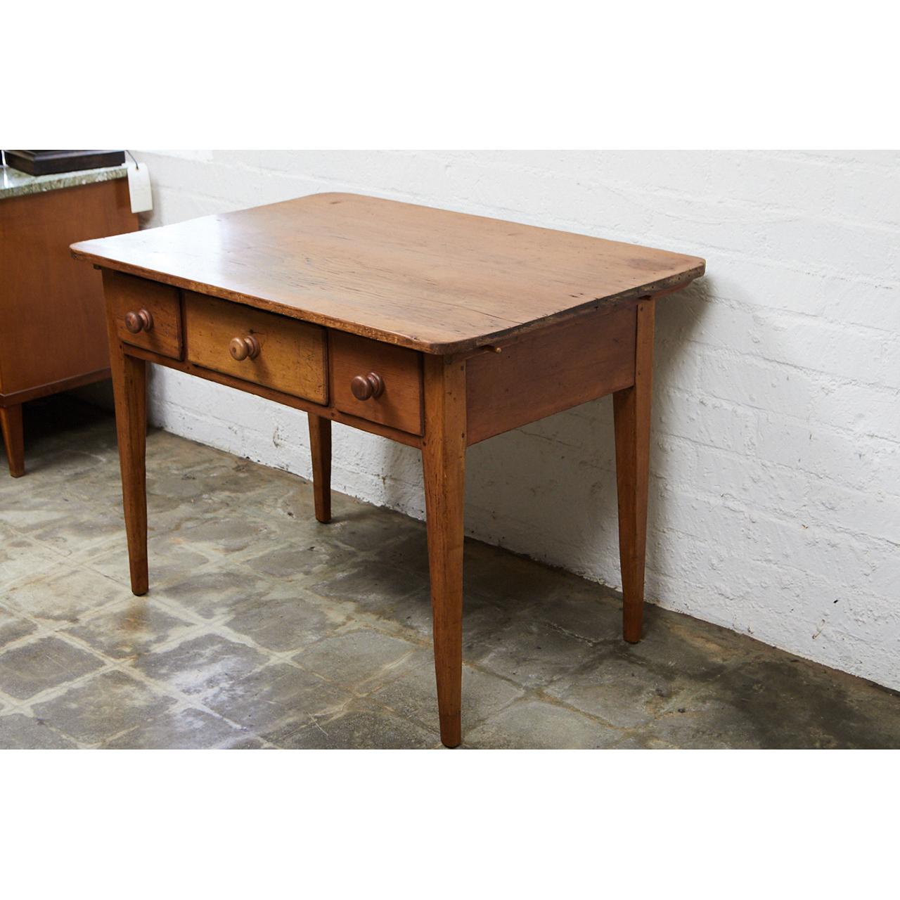 This mid-19th century Irish table/desk is a well crafted piece of pine furniture. The piece has three doors with turned wooden knobs and four tapered legs. The table has nice signs of wear indicative of it's age.
  