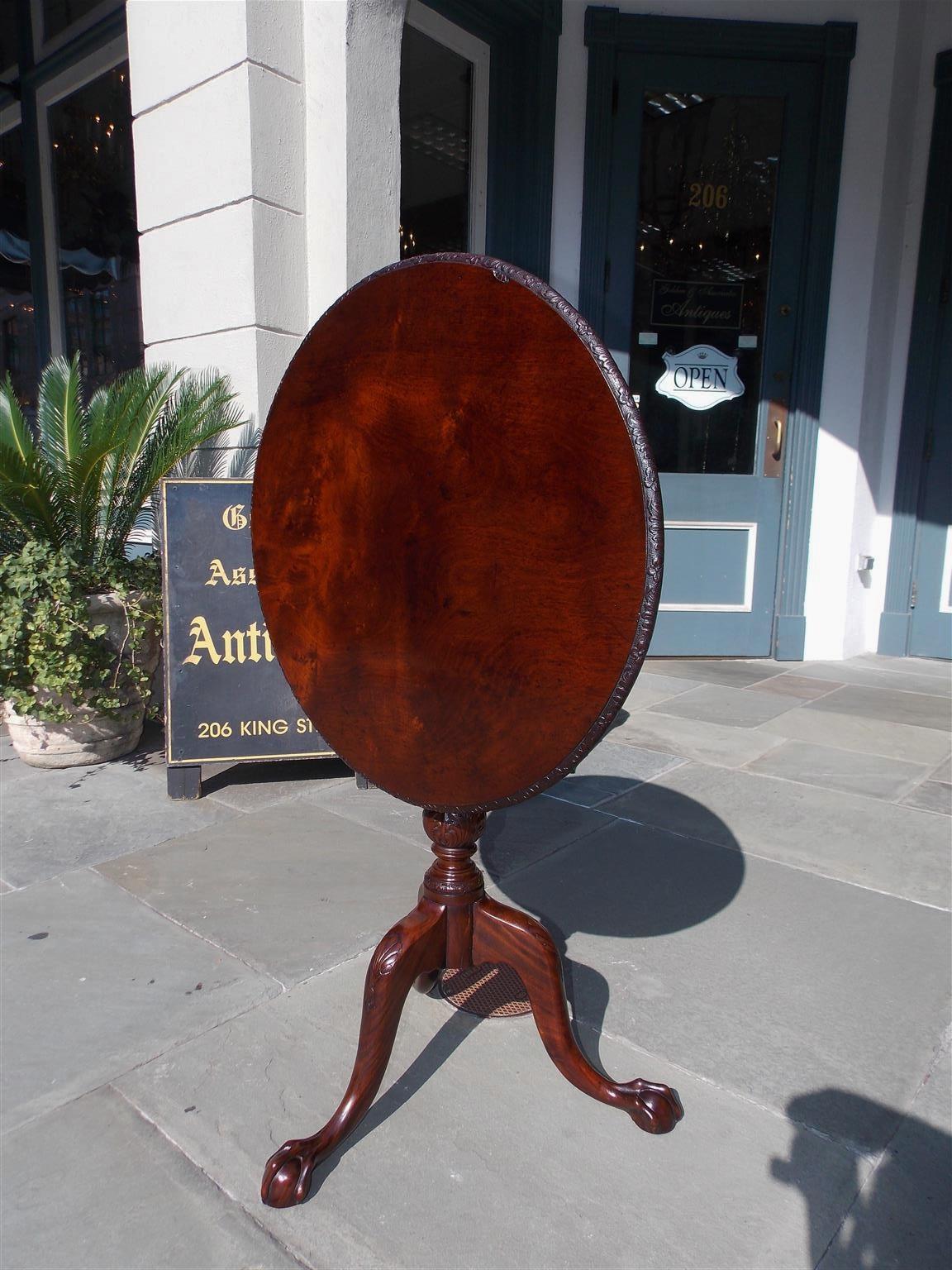Irish plum pudding mahogany tilt-top tea table with a carved floral molded edge, original brass locking mechanism, rotating birdcage, bulbous carved acanthus pedestal, and resting on shell carved knees with claw and ball feet, Late 18th century.