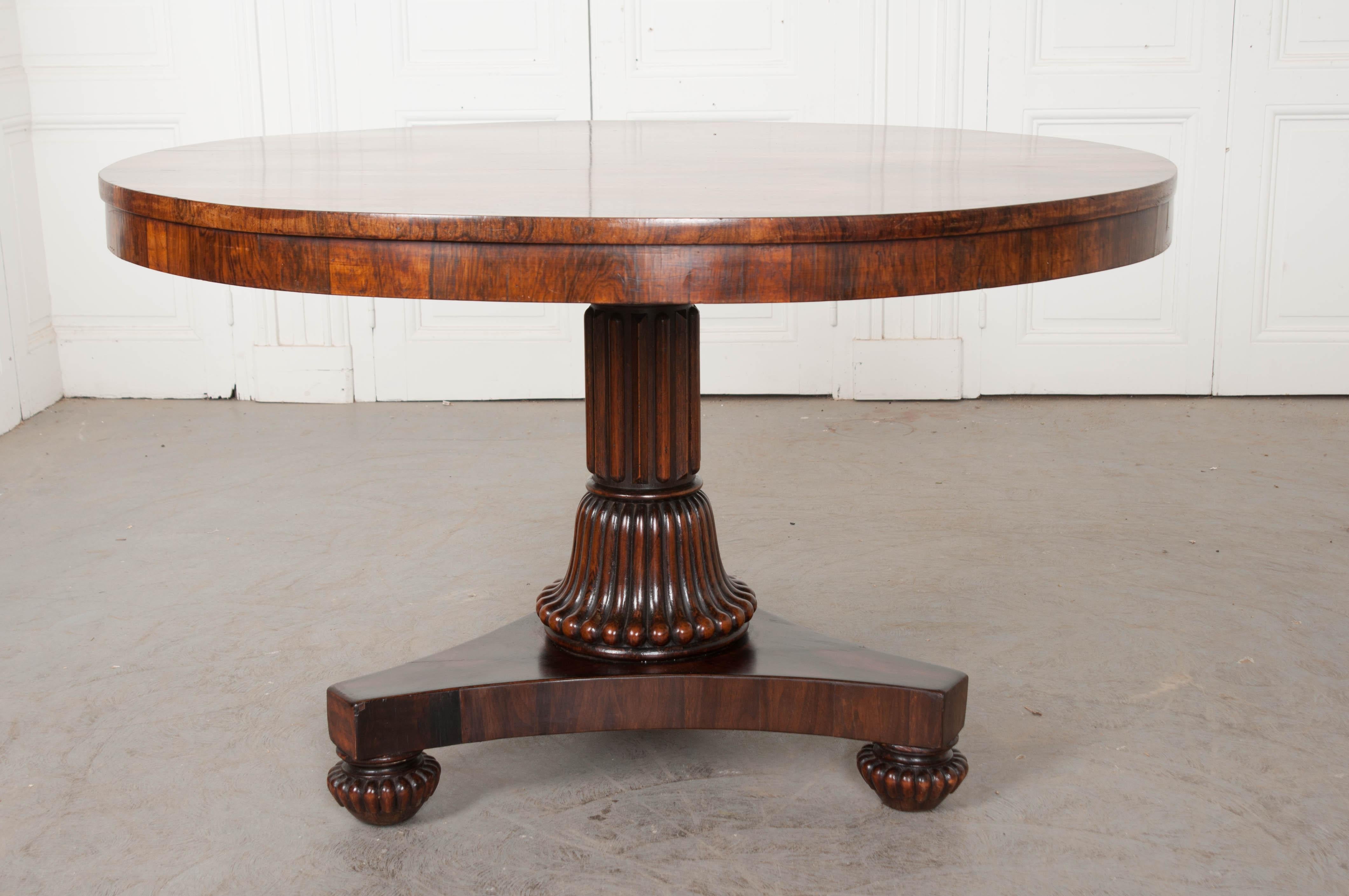 This exceptional Irish Regency figured rosewood center table, by Gillingtons of Dublin, circa 1815-1838, features a finely figured circular tilt-top with excellent patina and substantial brass handled on the underside, cross-grained rim, and