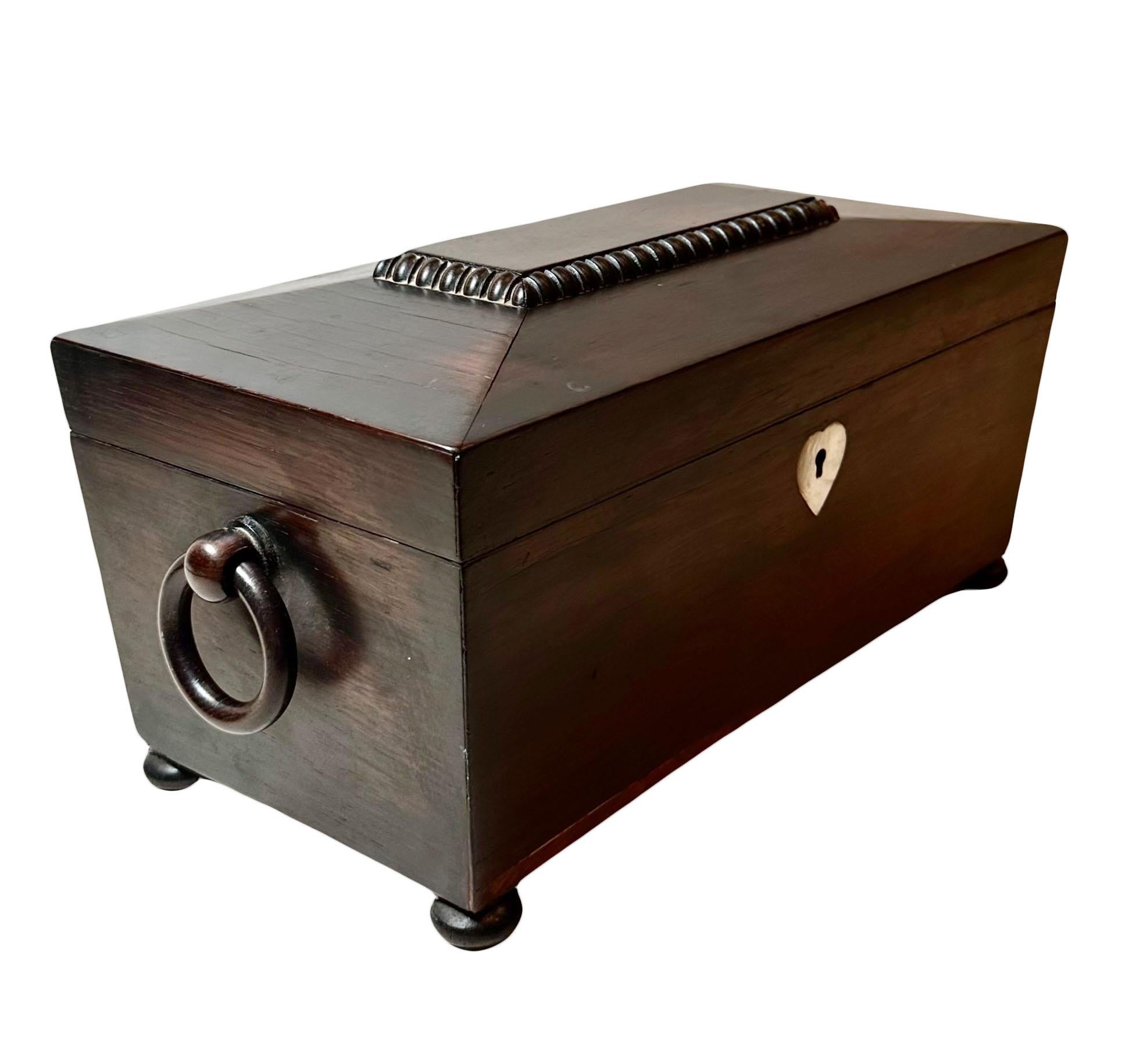A beautiful Irish 19th century rosewood tea caddy has its original glass and all of its interior. A sarcophagus design sitting on button feet. With wooden handles and mother of pearl hart lock, no key. The containers are four inches deep. The glass
