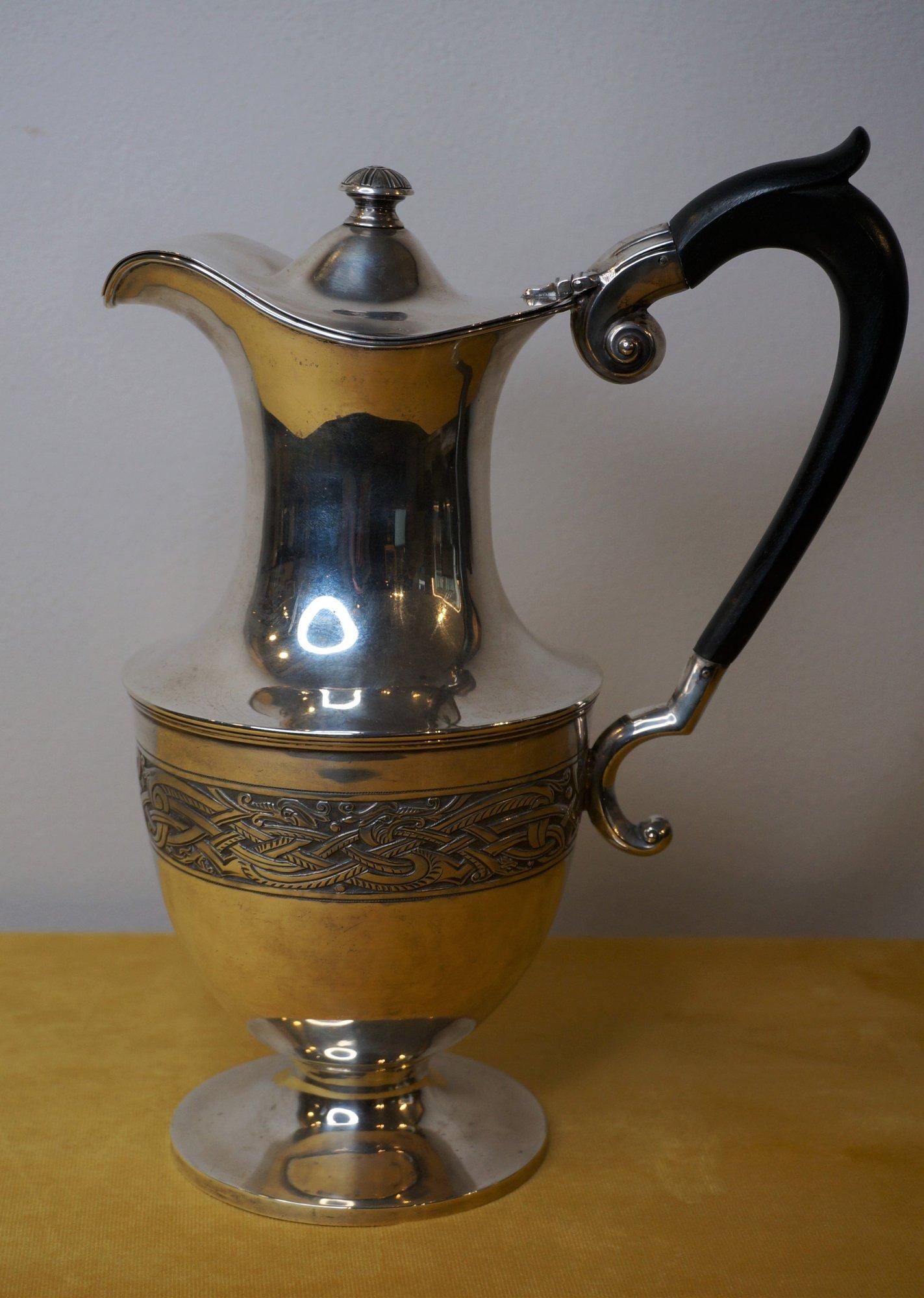 Irish sterling silver wine jug, decorated with Celtic motives with geometrical shapes and dragons, made by the famous Weir & sons company in Dublin. With blackened-wooden handle.

The jug might have been part of a church altar service.

Marked