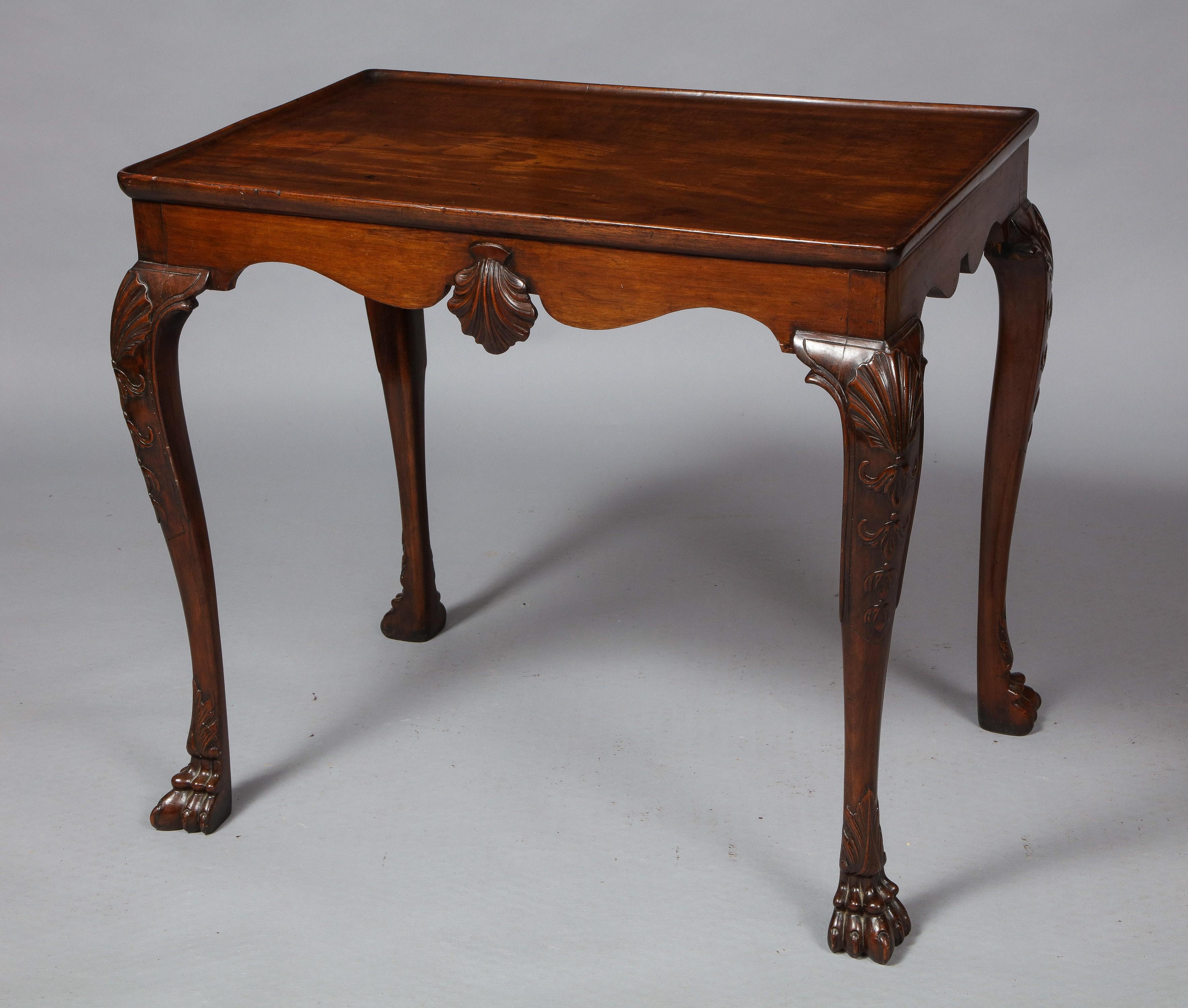 Very fine Irish mahogany tea table, the dished top with molded edge over scalloped apron, the two long sides with richly carved scallop shells and standing on cabriole legs with shell carved knees and ending in lion paw feet, the whole with good
