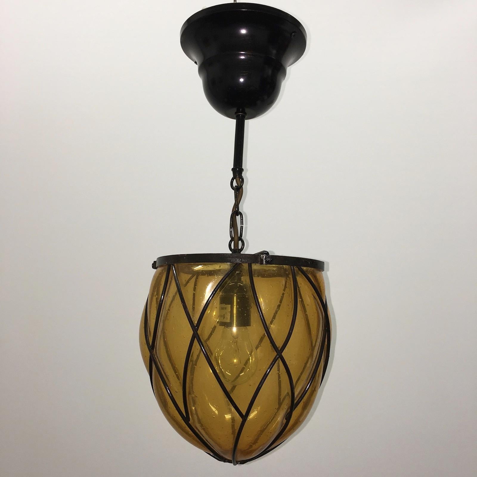 Magnifique lanterne de hall en fer et verre bullé ambré. Une belle addition à chaque maison ou foyer. Ce luminaire est en très bon état, avec des traces d'usure sur le verre et une certaine patine sur le cadre en fer. Le luminaire nécessite une