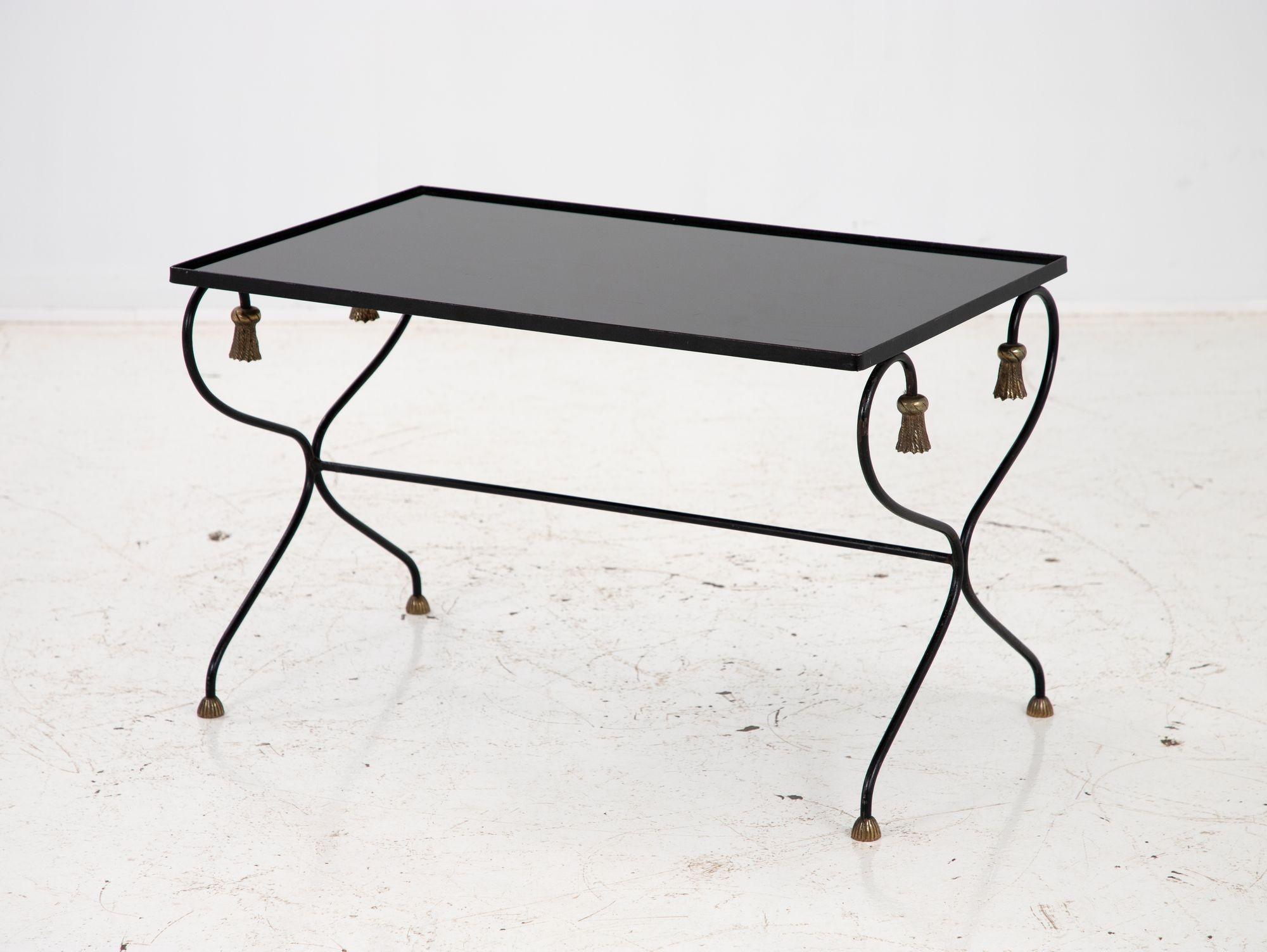 A 20th Century iron and black glass cocktail table is a stunning piece of furniture that will make a bold statement in any living space. This table features a sleek black glass top that offers space for displaying your favorite decor items or