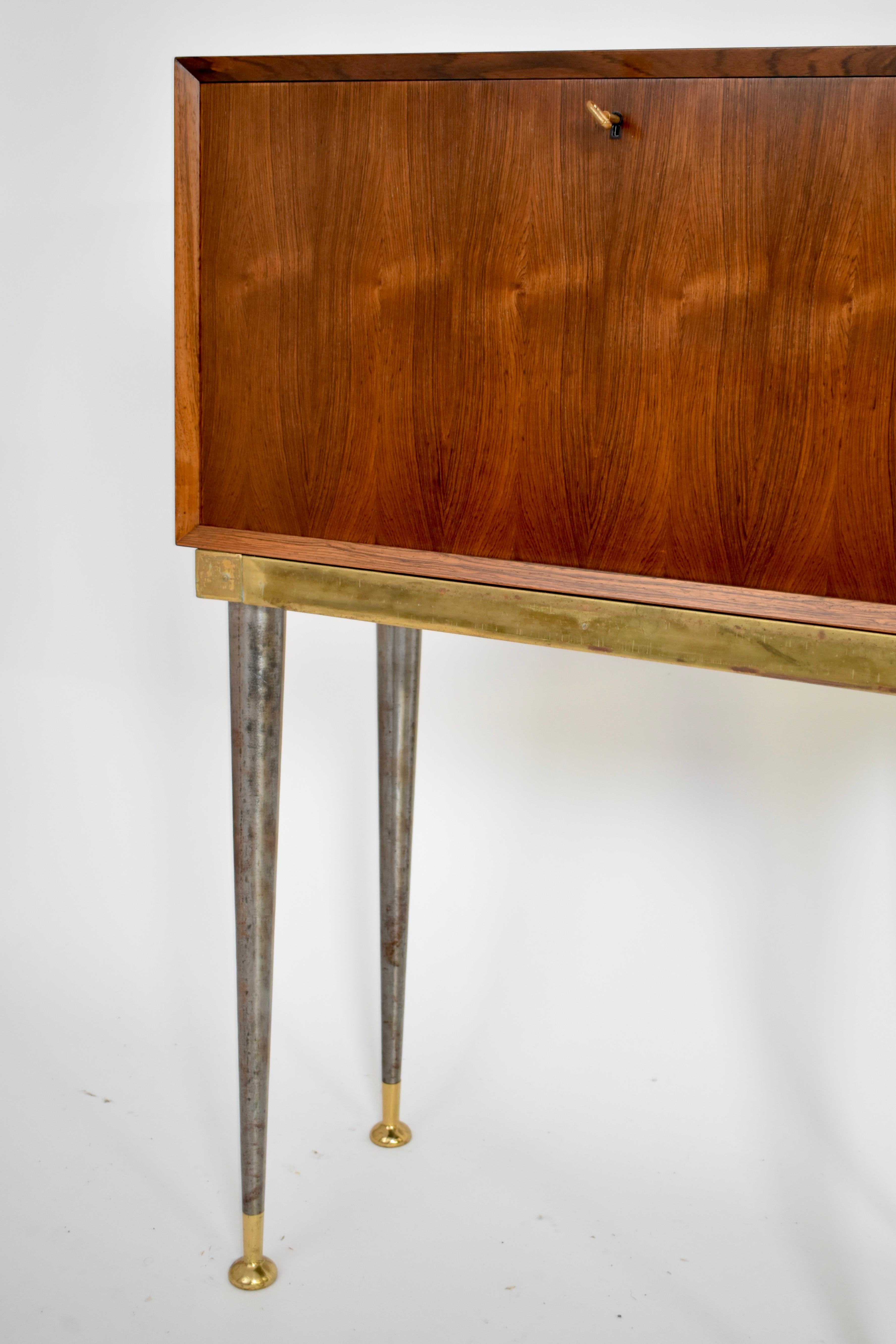Mueble escritorio de madera de viaje que se abre por delante para convertirse en una mesa de escritorio apoyada en una pata de hierro y latón. Dinamarca, años 60.